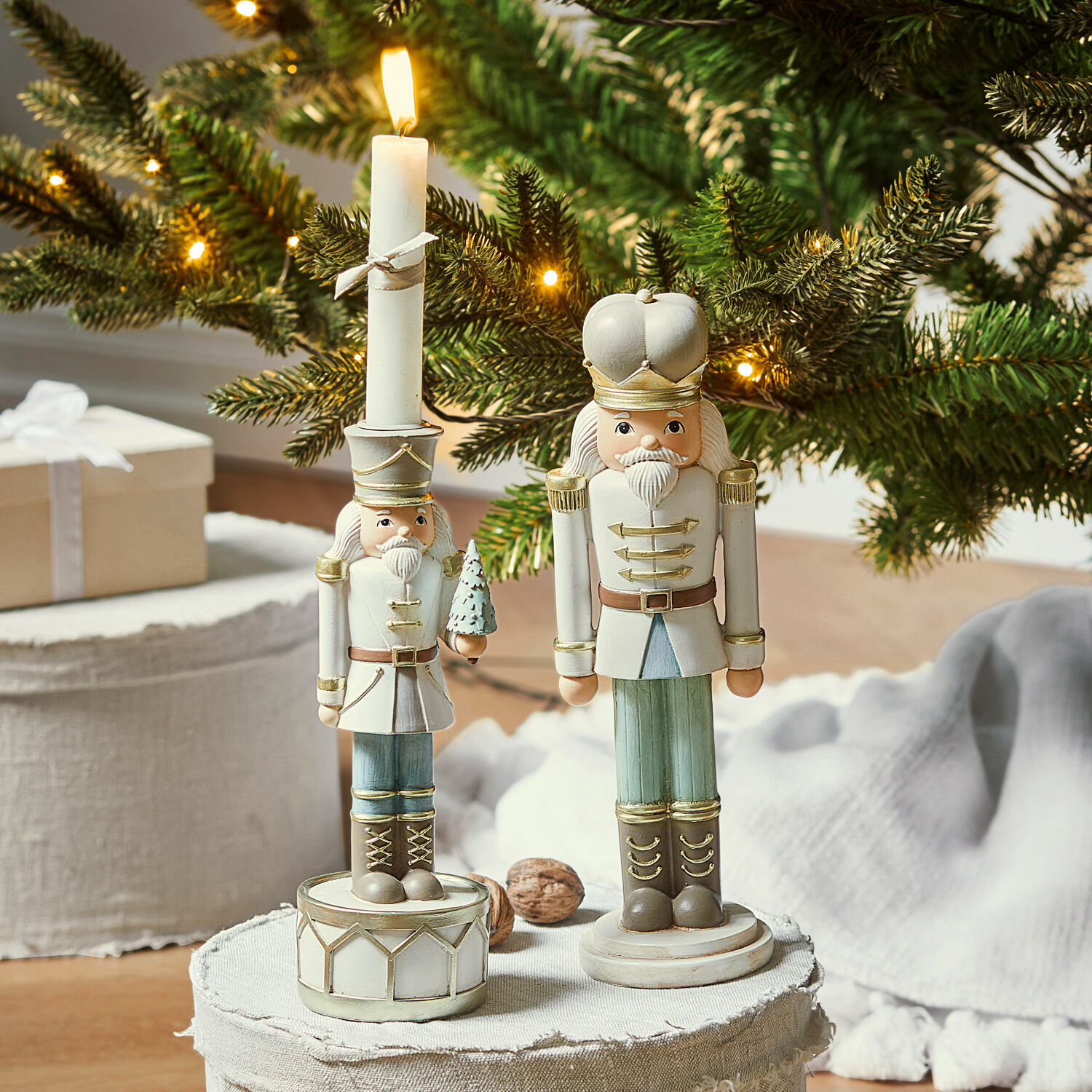 Siernotenkraker met kaarsenhouder Ellicott Houten notenkrakerfiguren in wit en groen voor een kerstachtergrond met verlichte dennentakken
