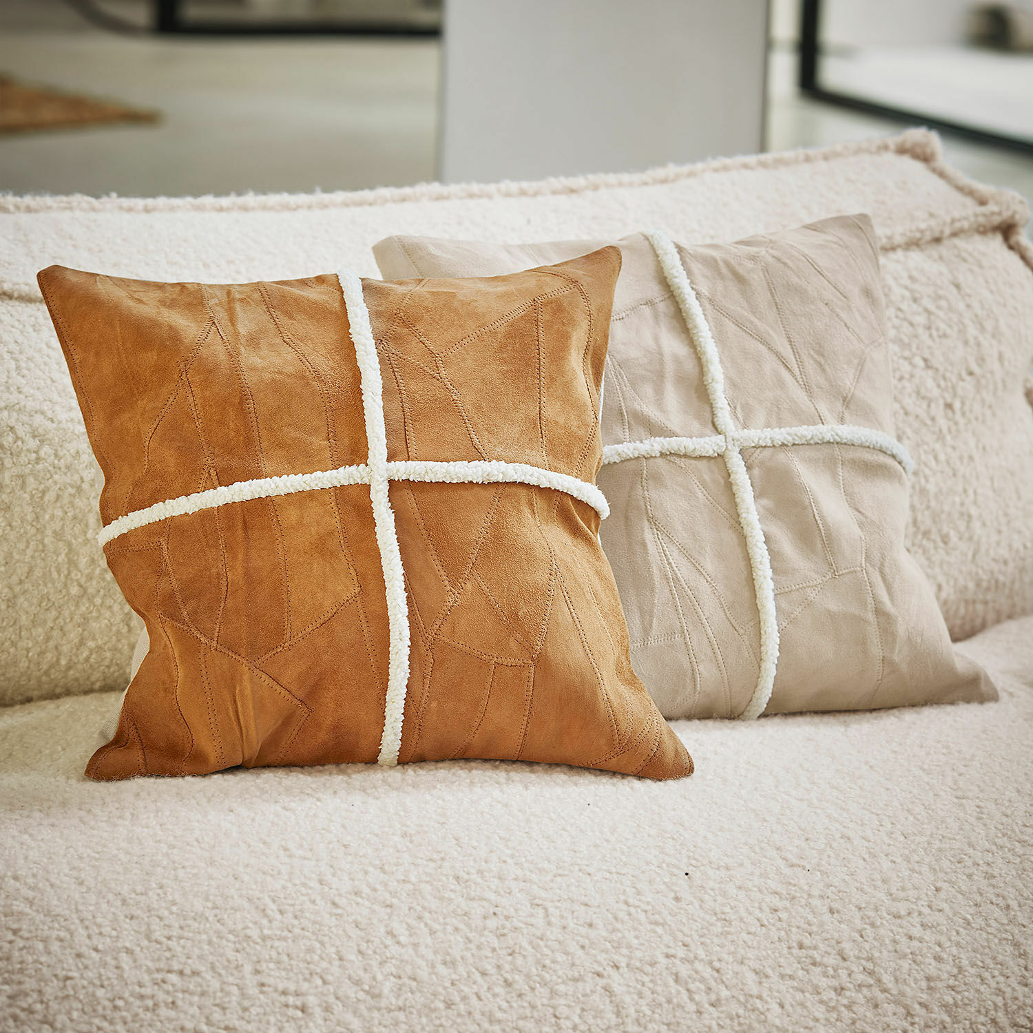 Lot de 2 housses de coussins Raminya Deux coussins décoratifs en daim marron et beige avec bandes blanches sur un canapé douillet