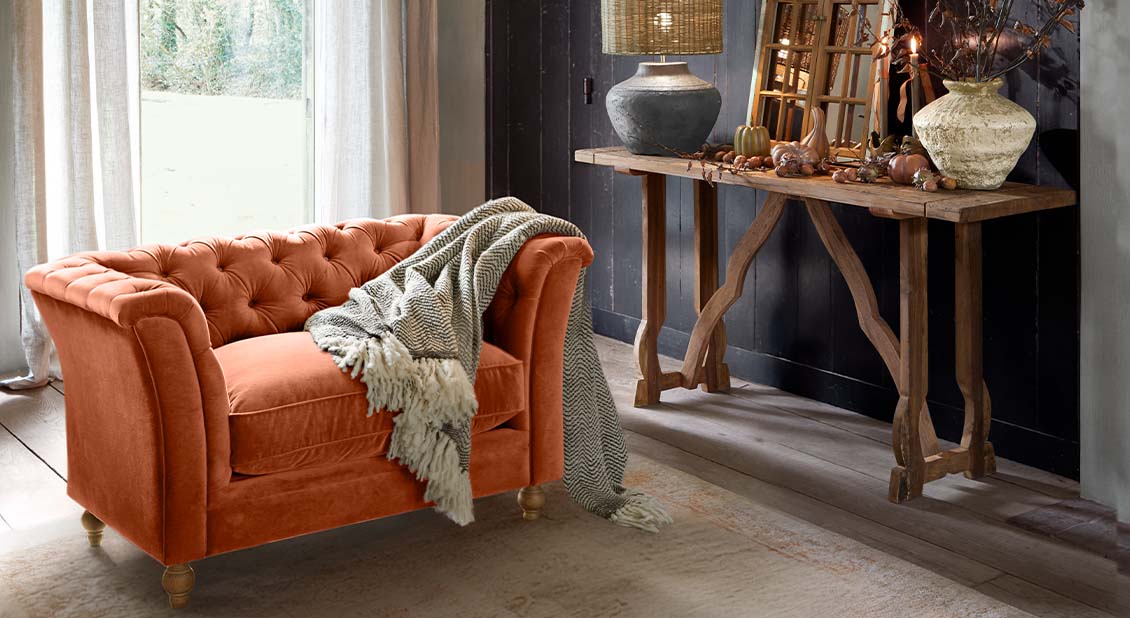 Canapé en velours orange brûlé avec dossier capitonné et plaid gris dans un salon chaleureux