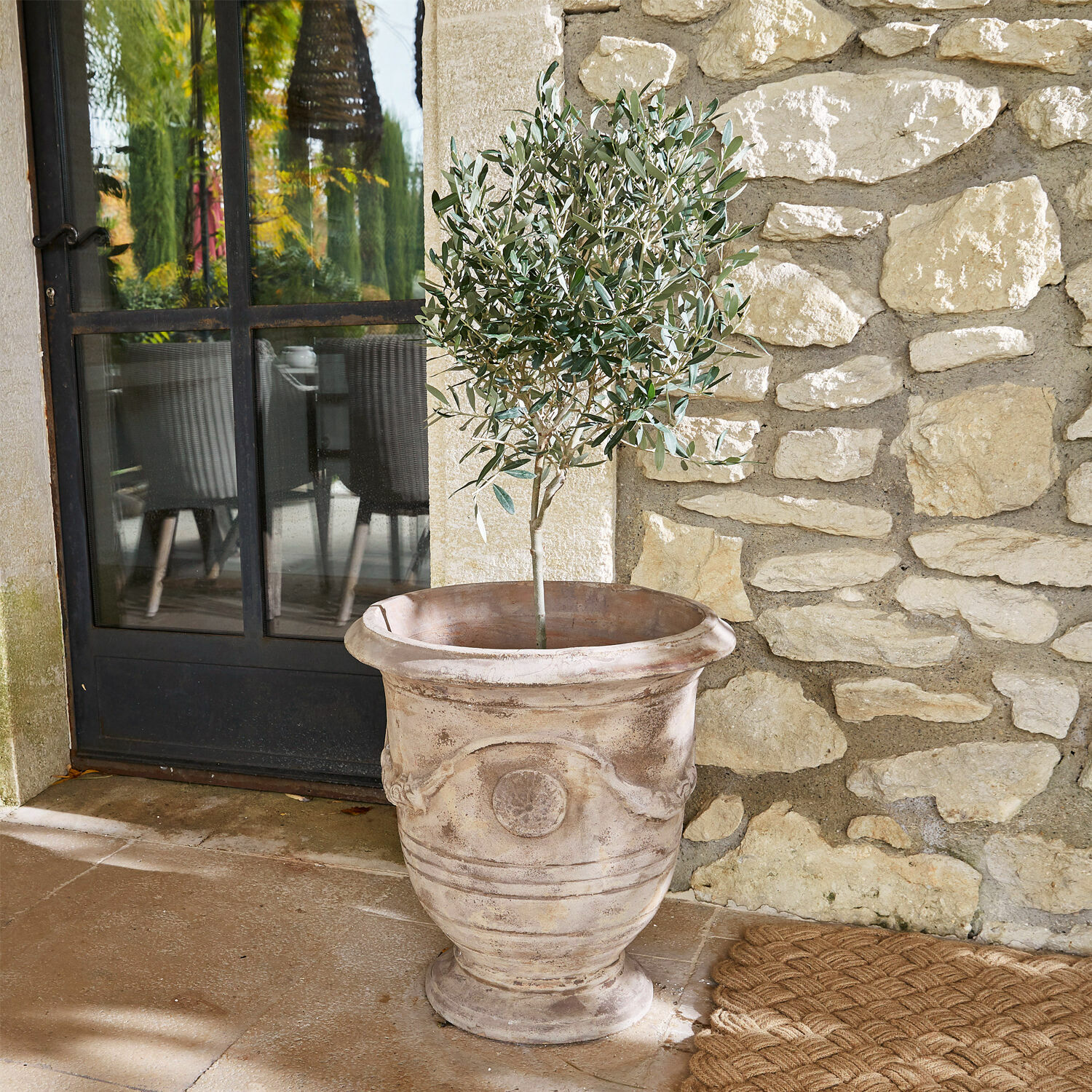 Sierpot Garwood Grote decoratieve terracotta bloempot in beige met groene plant op stenen terras