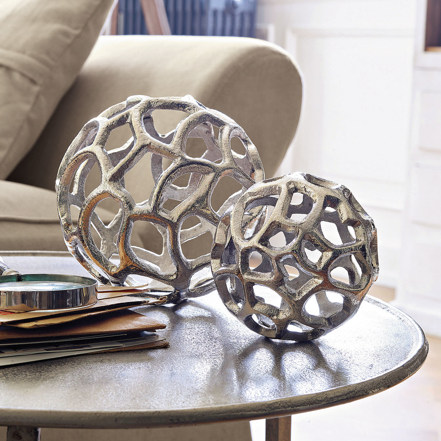Lot de 2 décorations Venay Boules décoratives en métal ajouré argenté posées sur une table basse dans un salon