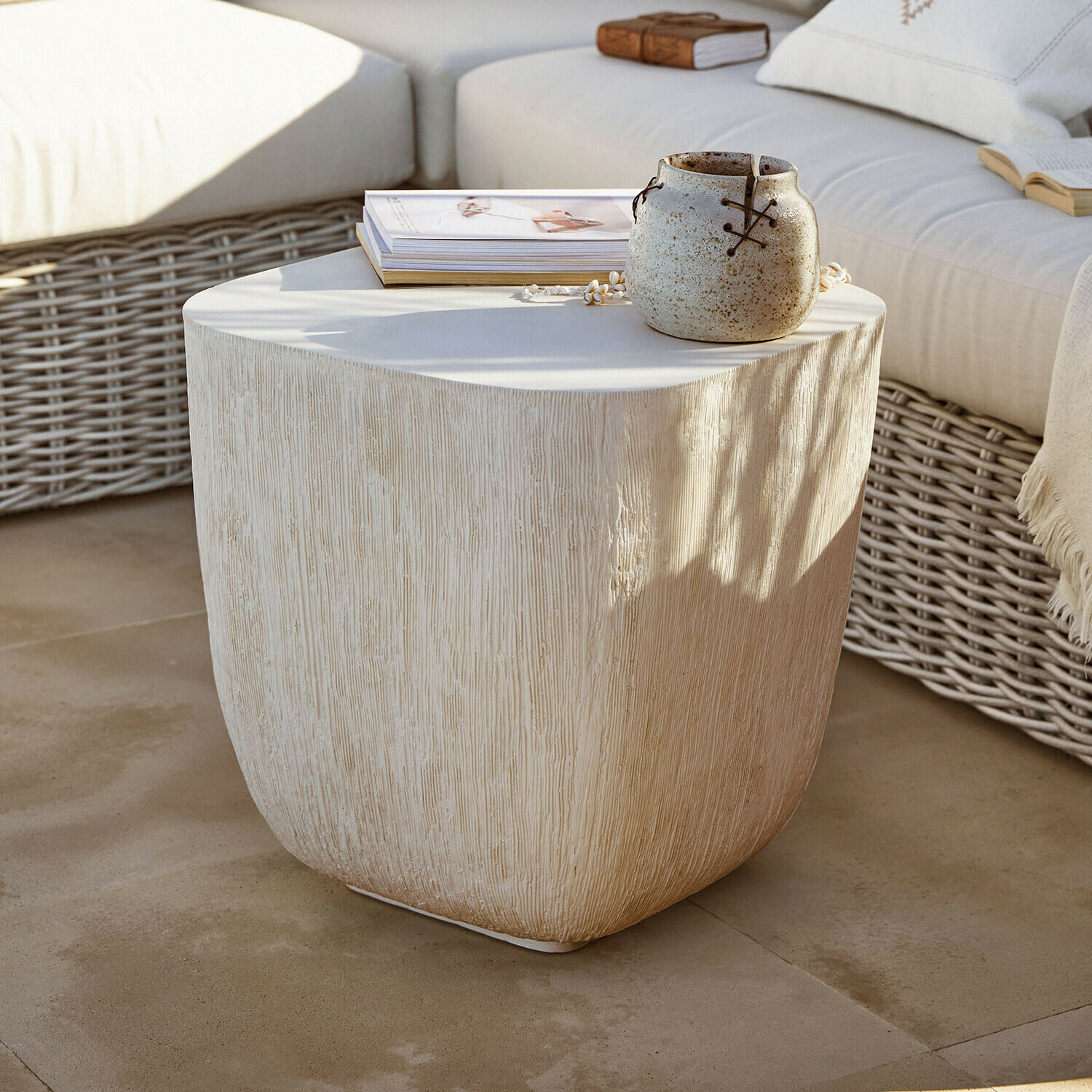 Bijzettafeltje Nélomiane Beige bijzettafel met houtstructuur, keramische vaas en boeken op terras met rotan bank