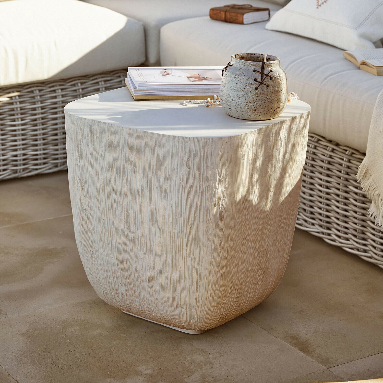 Bijzettafeltje Nélomiane Beige bijzettafel met houtstructuur, keramische vaas en boeken op terras met rotan bank