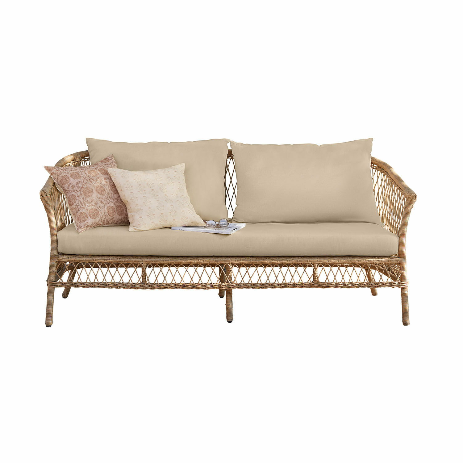 Canapé en rotin avec coussins beige et coussins décoratifs aux tons pastel doux