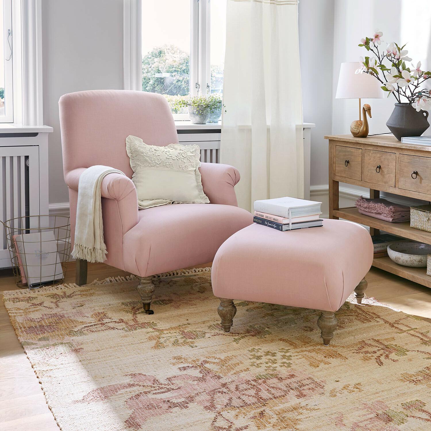 Fauteuil met hocker Rose de Lumière Roze stoffen fauteuil en voetenbank in lichte woonkamer met houten tafel en decoratie