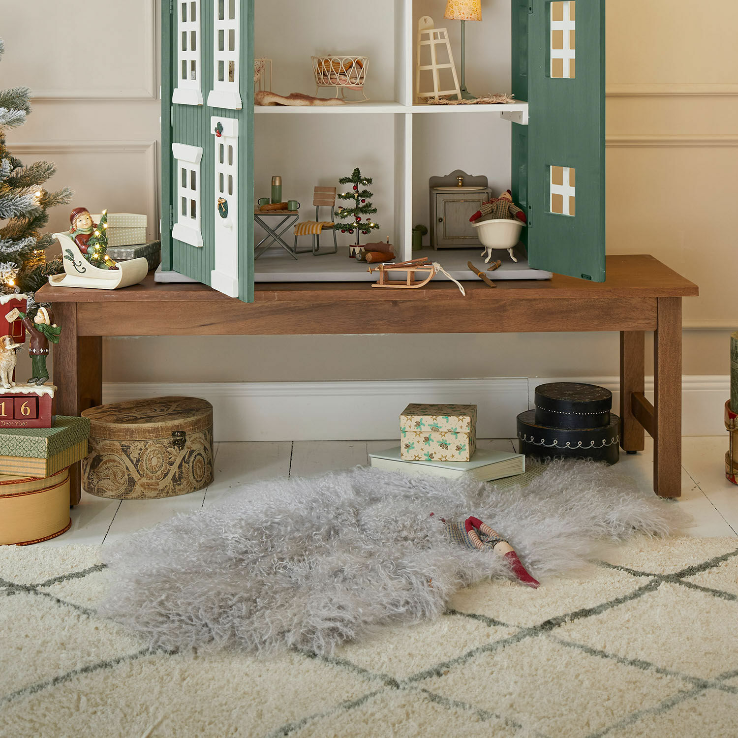 Bankje Noireval Grijs zacht wollen vloerkleed op de vloer onder een houten tafel met poppenhuis en kerstdecoratie