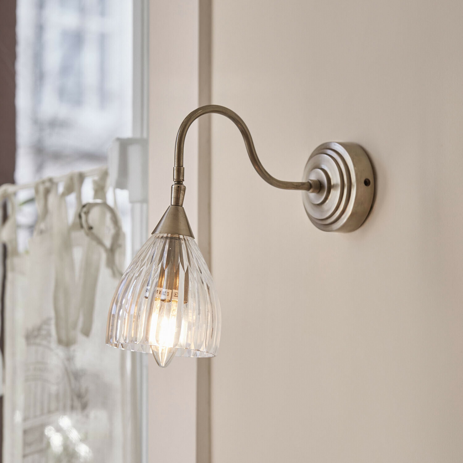 Wandlamp Niamhs Wandlamp met doorzichtige glazen kap en metalen arm in antiek zilverkleurig ontwerp