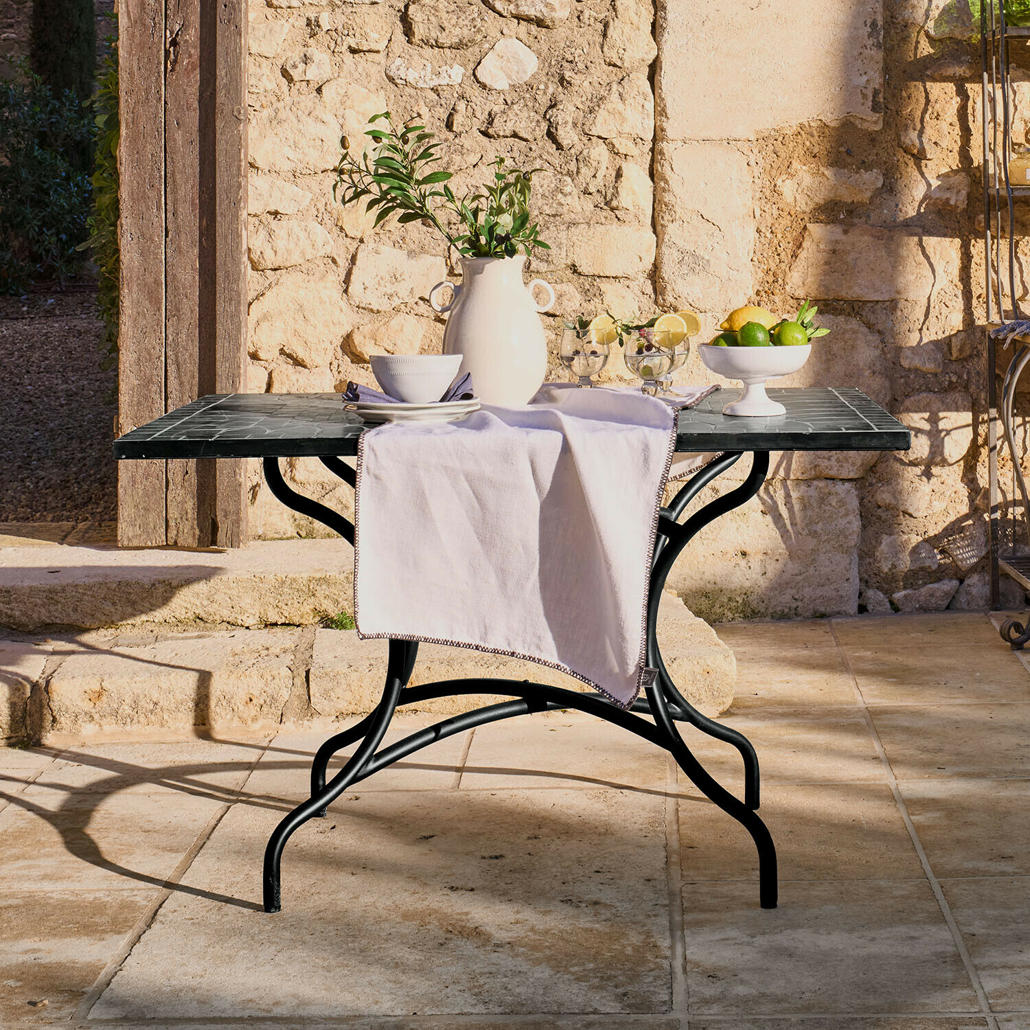 Tuin tafel met zwart metalen frame en marmeren blad, versierd met witte vaas en fruit