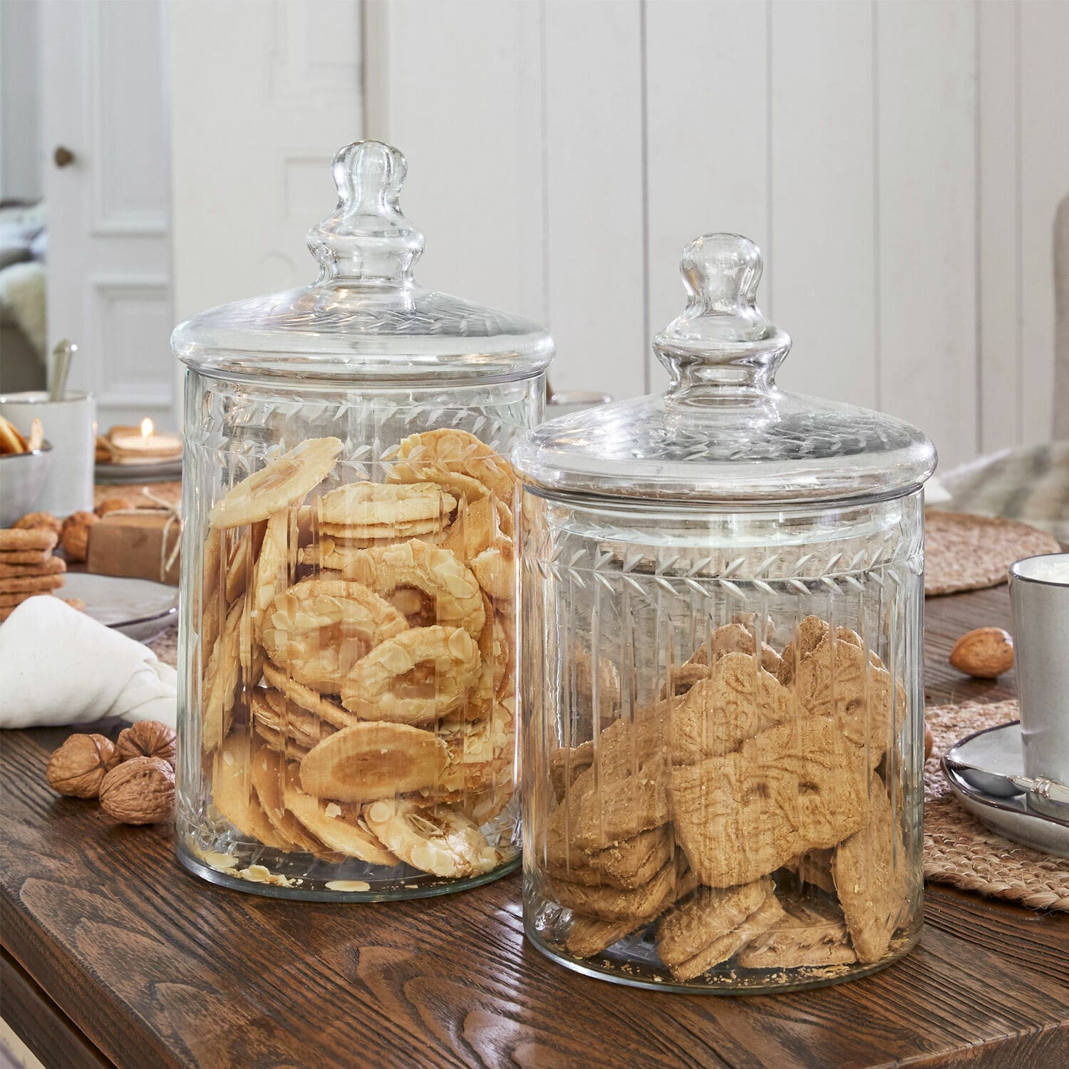 Transparante glazen potten met deksels gevuld met koekjes op een rustieke houten tafel