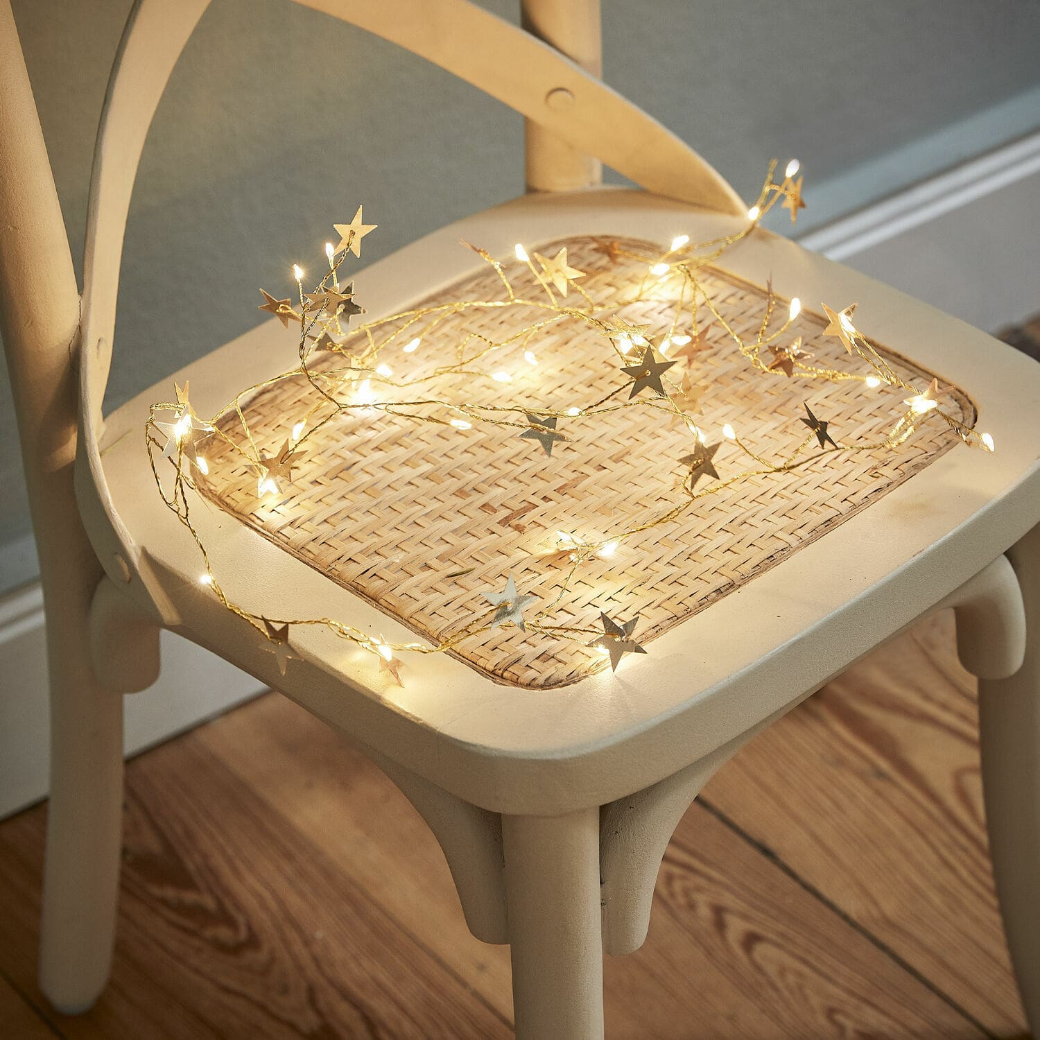 Guirlande lumineuse Vernham Guirlande lumineuse étoilée à lumière chaude posée sur une chaise en osier clair
