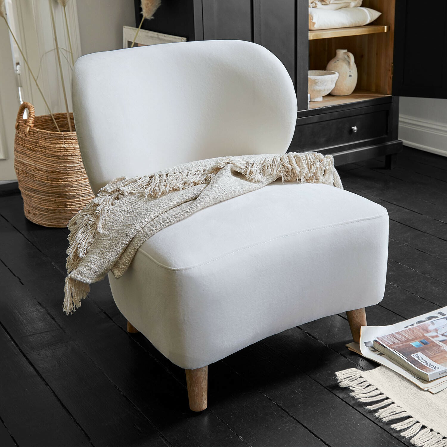 Fauteuil Seraluna Fauteuil blanc rembourré avec pieds en bois et plaid beige sur un sol noir dans un salon moderne