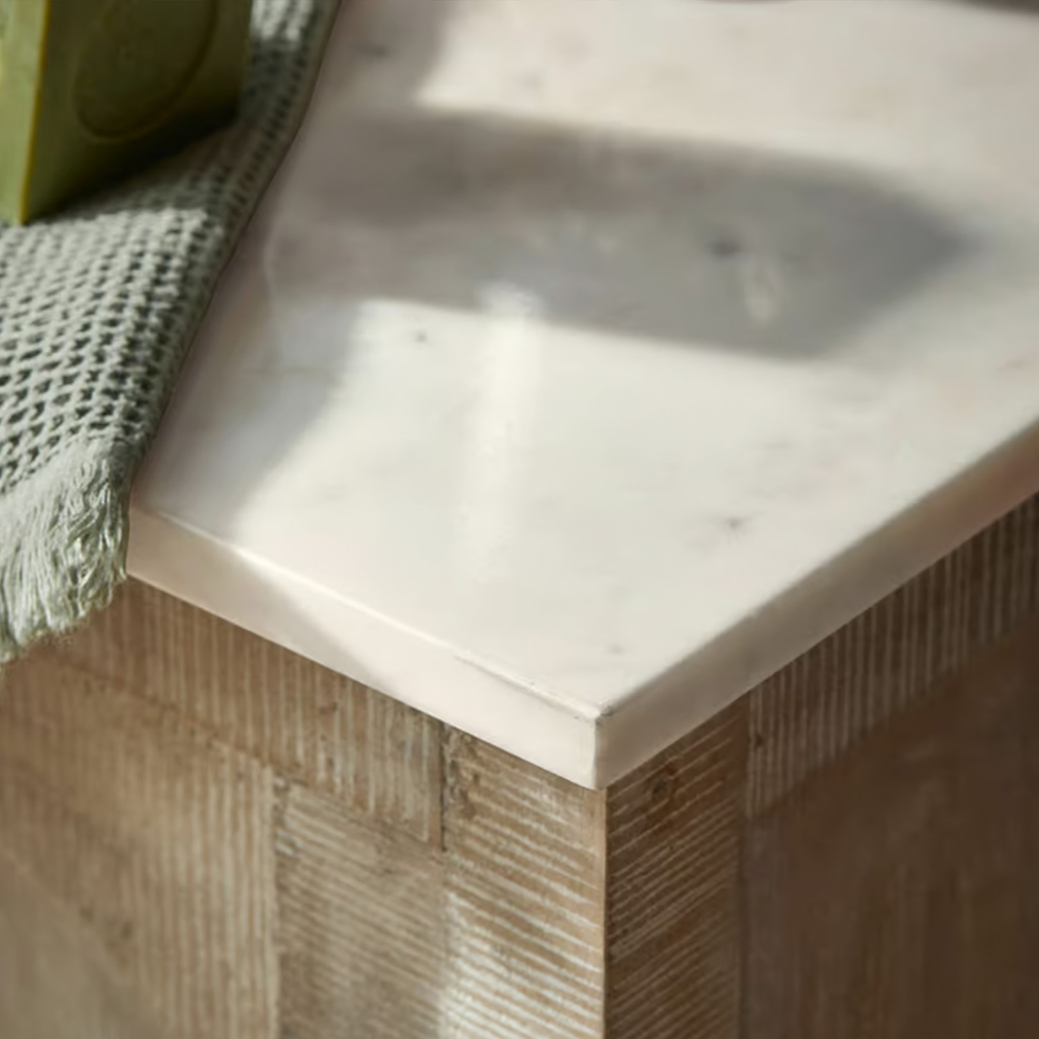 Plan de travail en marbre blanc sur base en bois avec serviette verte en tissu, meuble moderne