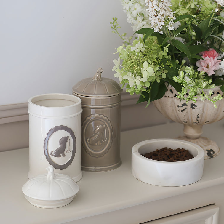 Boîtes en céramique crème et beige pour nourriture de chien avec bol blanc rempli de croquettes et bouquet de fleurs