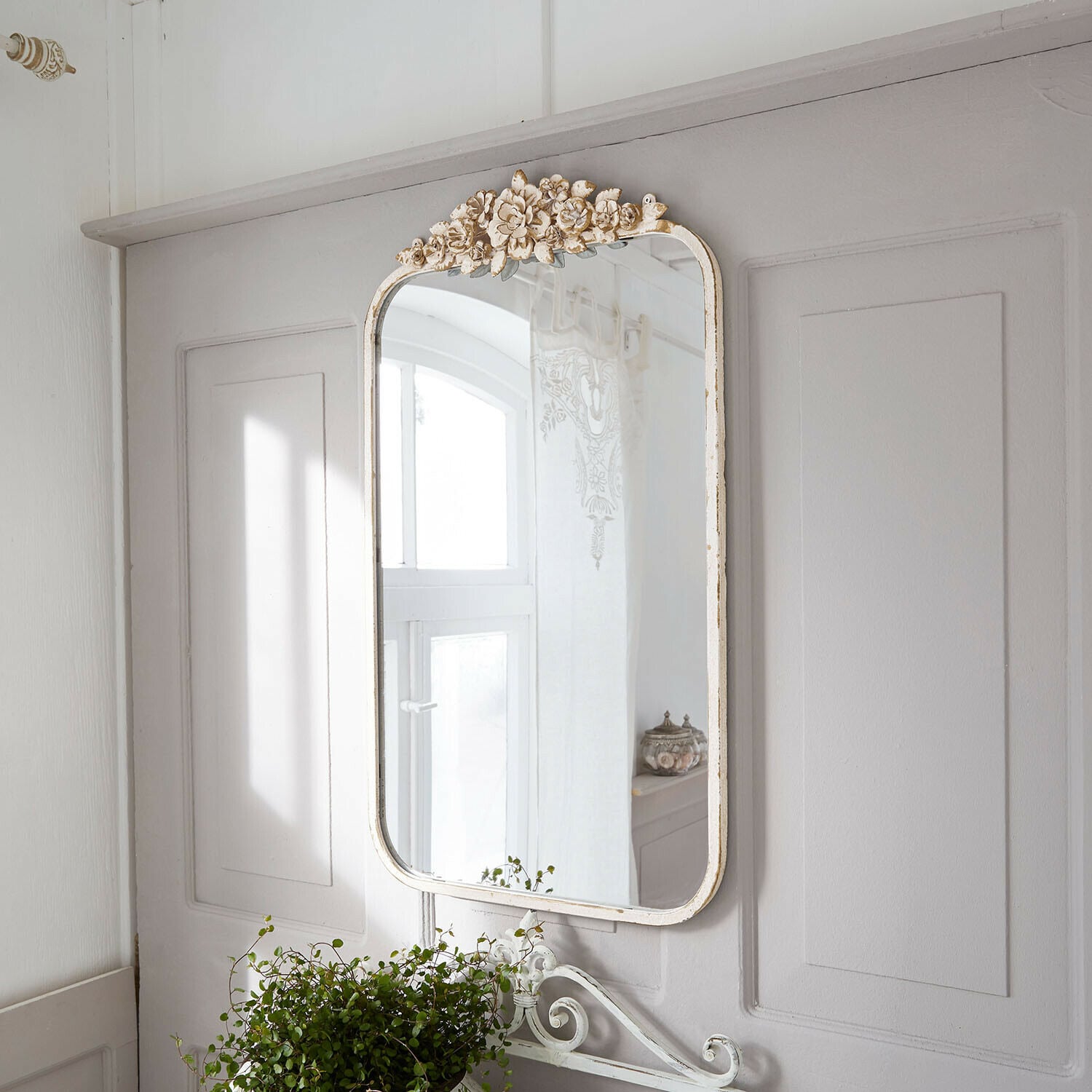 Decoratieve wandspiegel met witte verweerde lijst en bloemmotief in vintage stijl