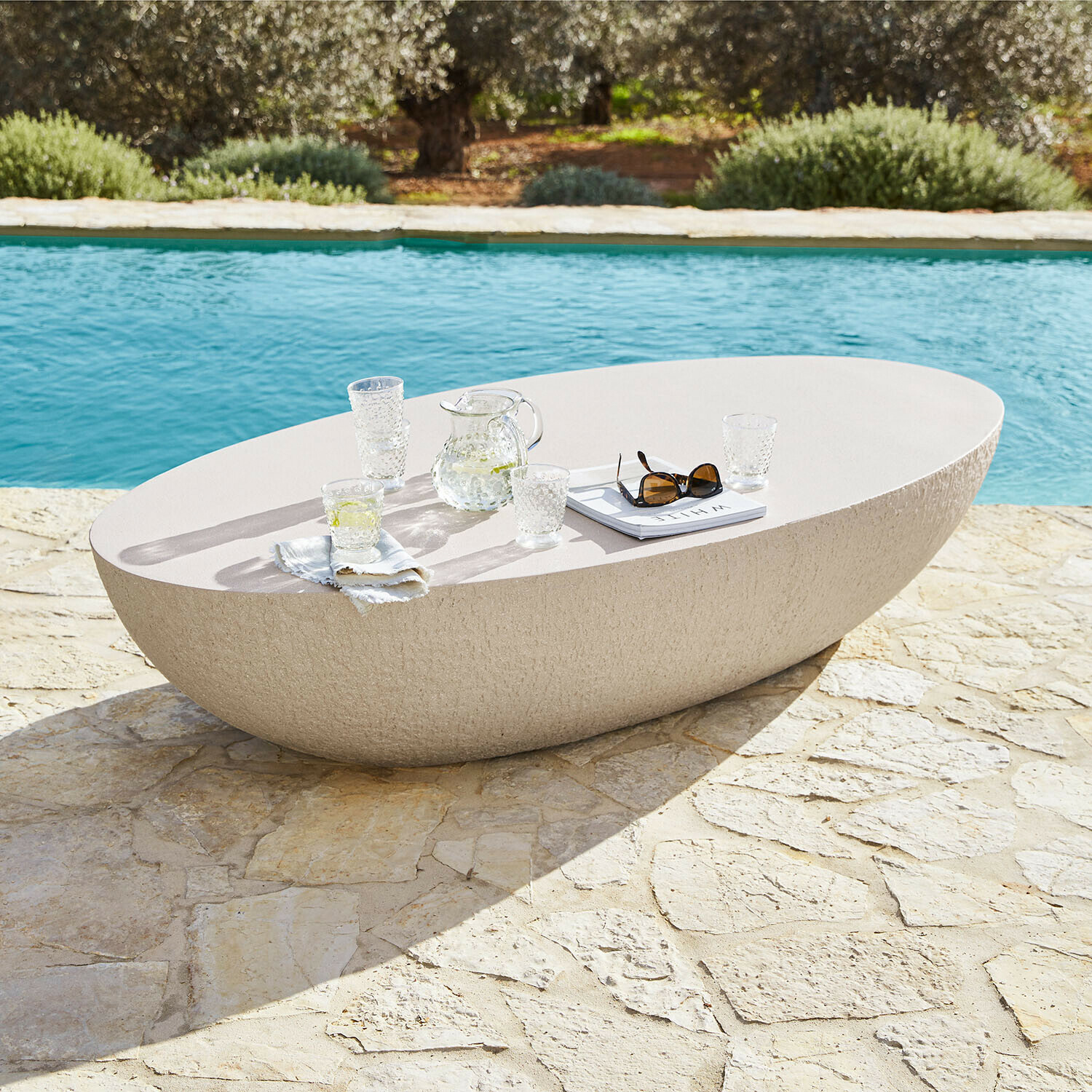 Table basse Maraveda Table ovale en pierre claire sur terrasse en pierre près de la piscine, mobilier extérieur moderne