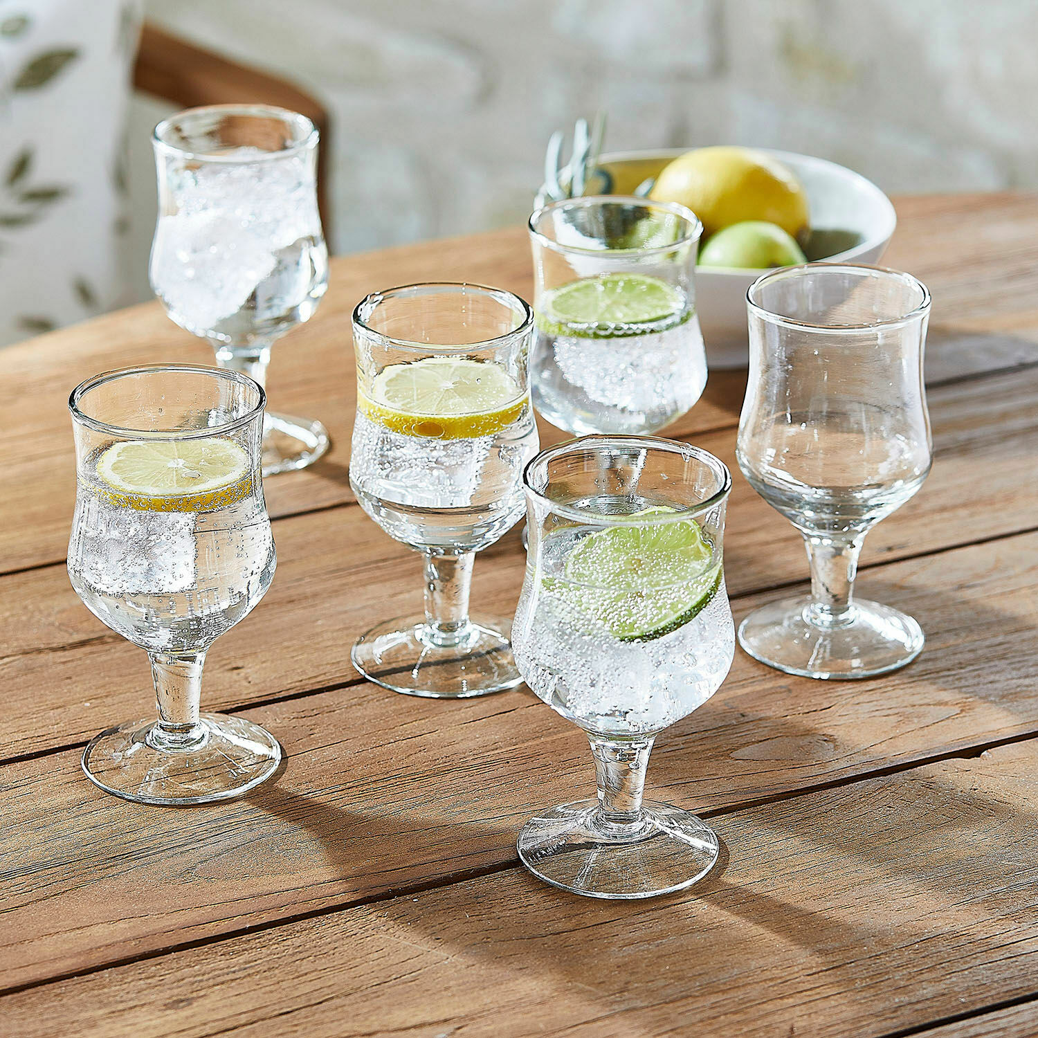 Glas set van 6 Gaëtane Set van zes heldere glazen op voet met schijfjes citroen en limoen op houten tafel