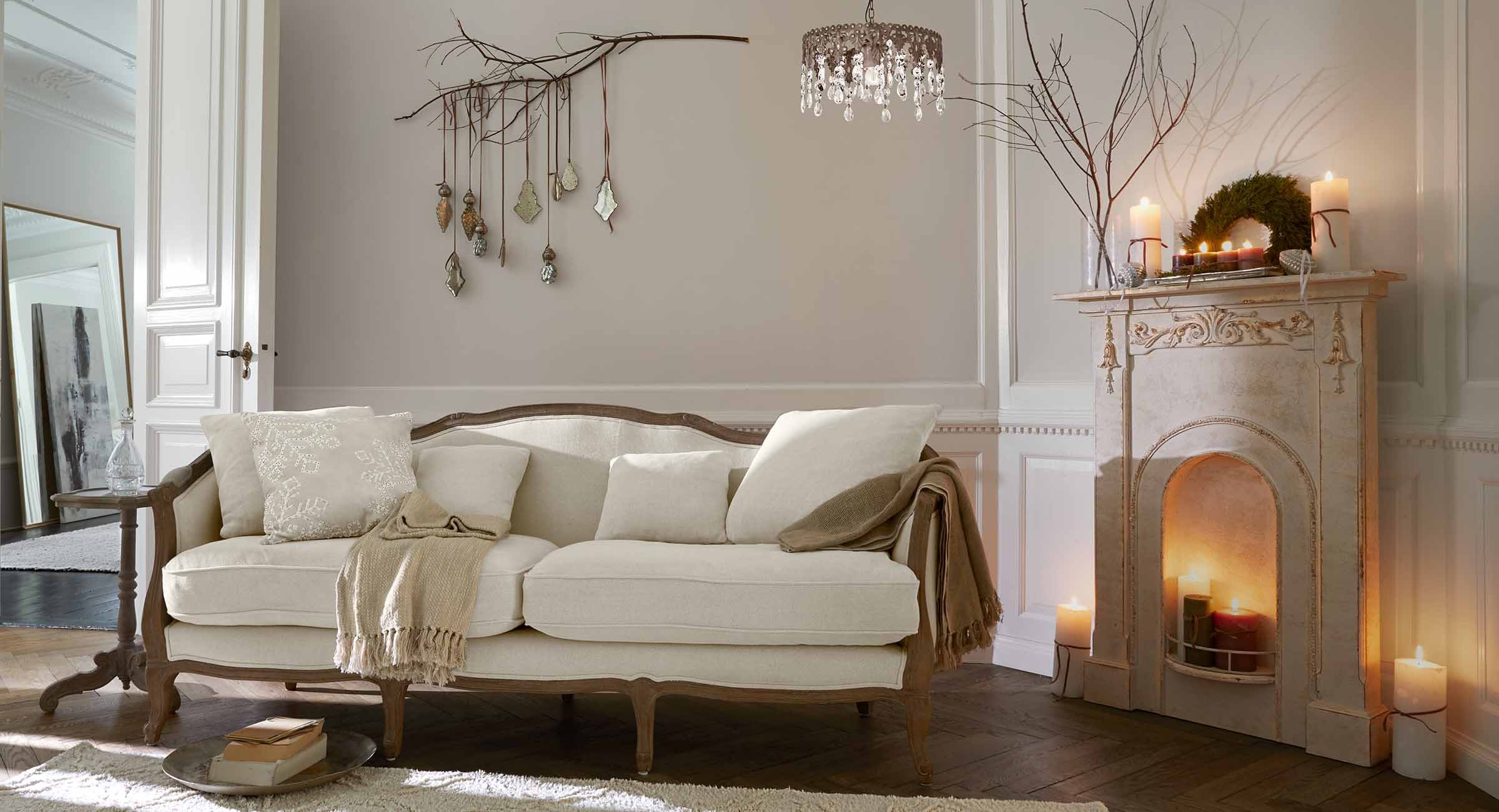Canapé beige avec cadre en bois dans un salon classique avec cheminée et décorations murales