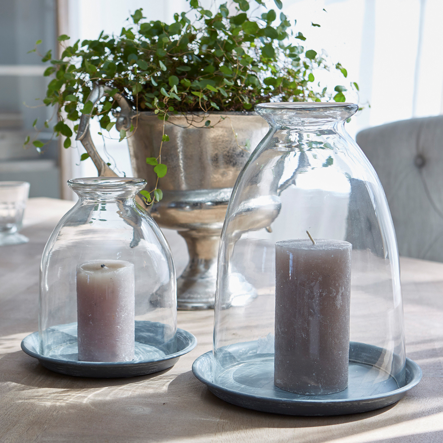 Bougies grises sous des cloches en verre transparent sur des plateaux métalliques sur une table