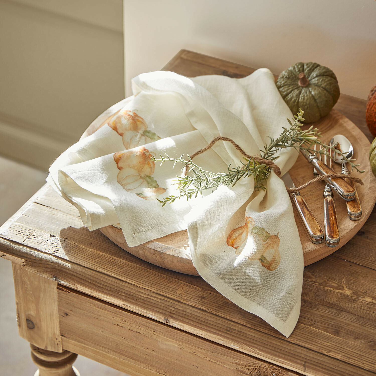 Lot de 4 serviettes Florrien Serviette en lin crème avec motif citrouille et décoration herbes sur plateau en bois avec couverts