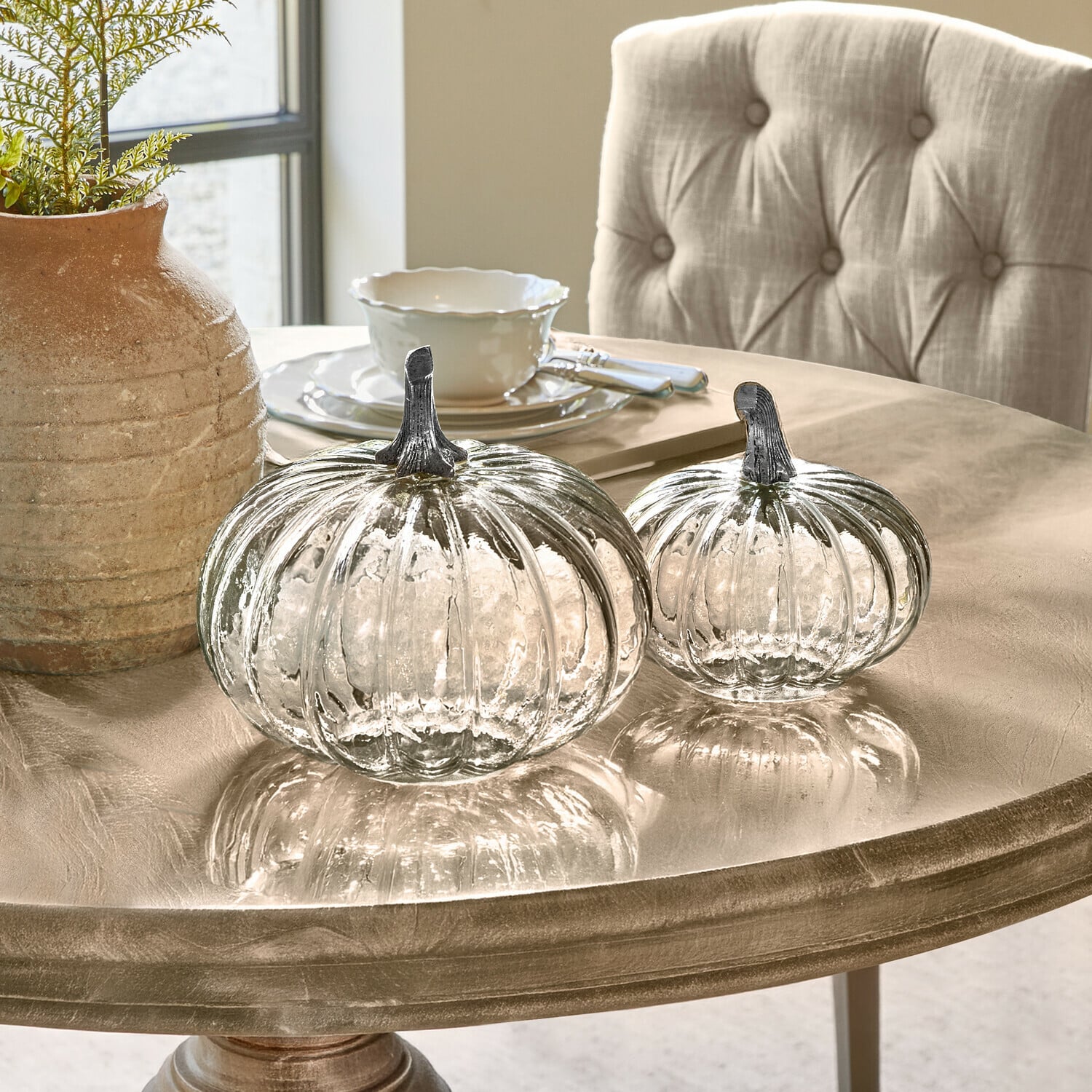 Lot de 2 citrouilles Perlouin Deux citrouilles en verre transparent avec tiges métalliques sur une table beige décorative