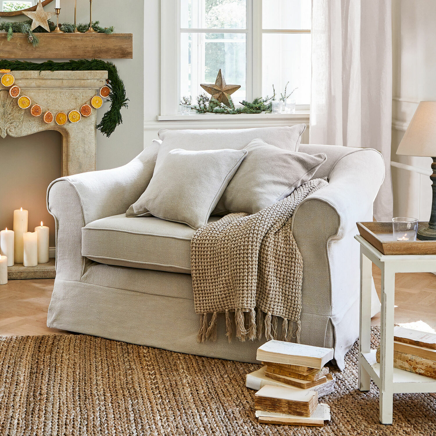 Fauteuil Folsom Beige stoffen bank met kussens en gebreide deken op jute vloerkleed in gezellige woonkamer