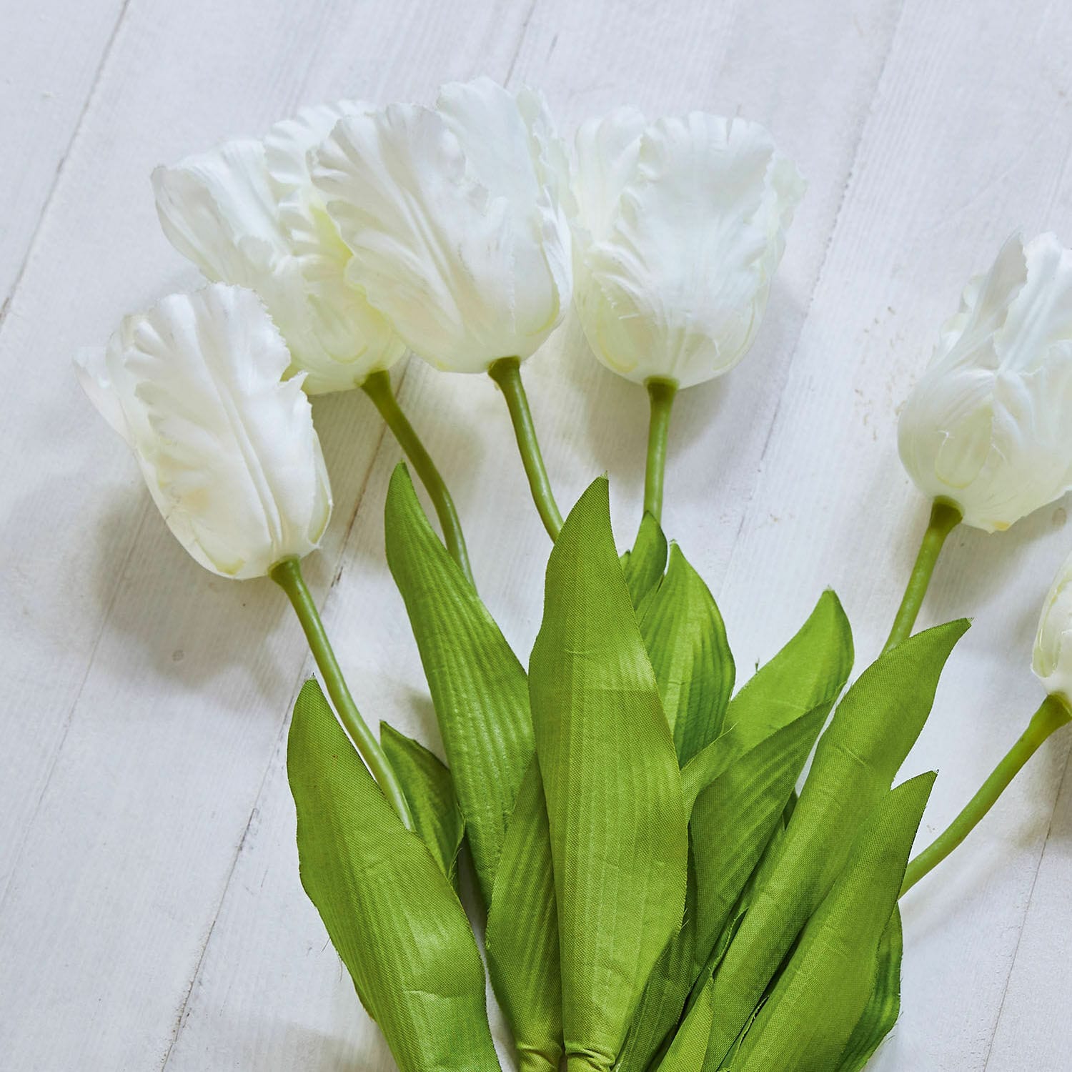 Boeket witte tulpen met groene bladeren op lichte achtergrond, lentehuisdecoratie