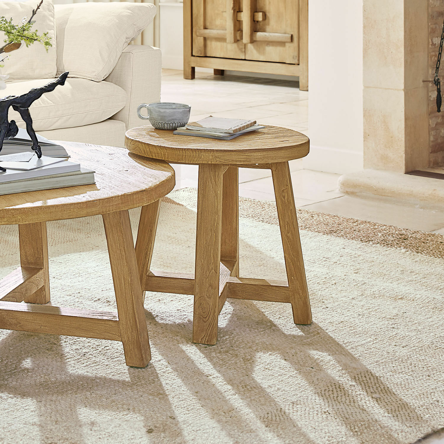 Bijzettafel Gorivel Ronde houten salontafel in natuurlijke kleur op lichte vloerkleed bij beige bank in woonkamer