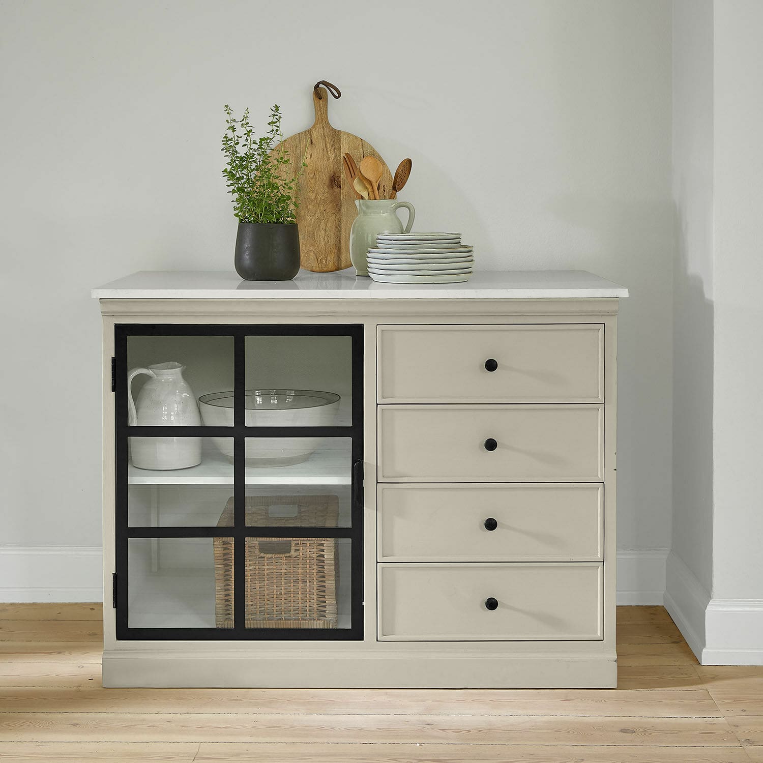 Kast Orlévine Beige dressoir met zwarte handgrepen en glazen deur, gedecoreerd met houten plank en groene plant