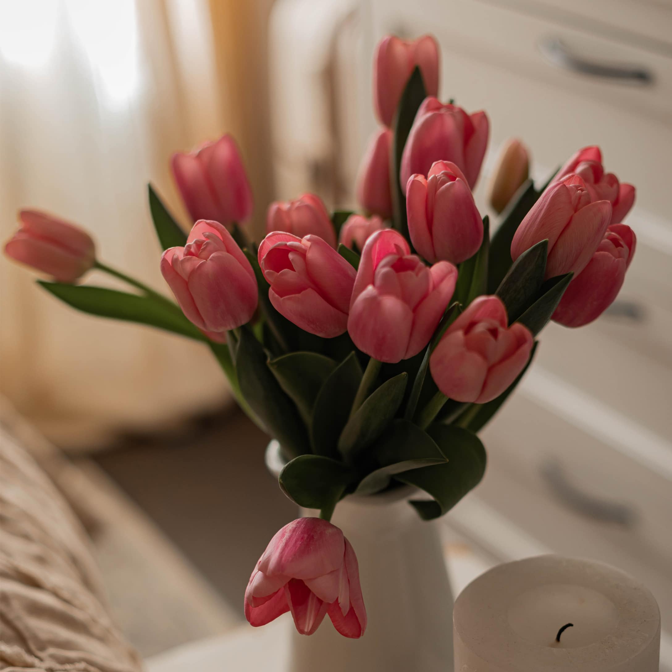 Bouquet de tulipes roses dans un vase blanc dans une chambre lumineuse et décorée