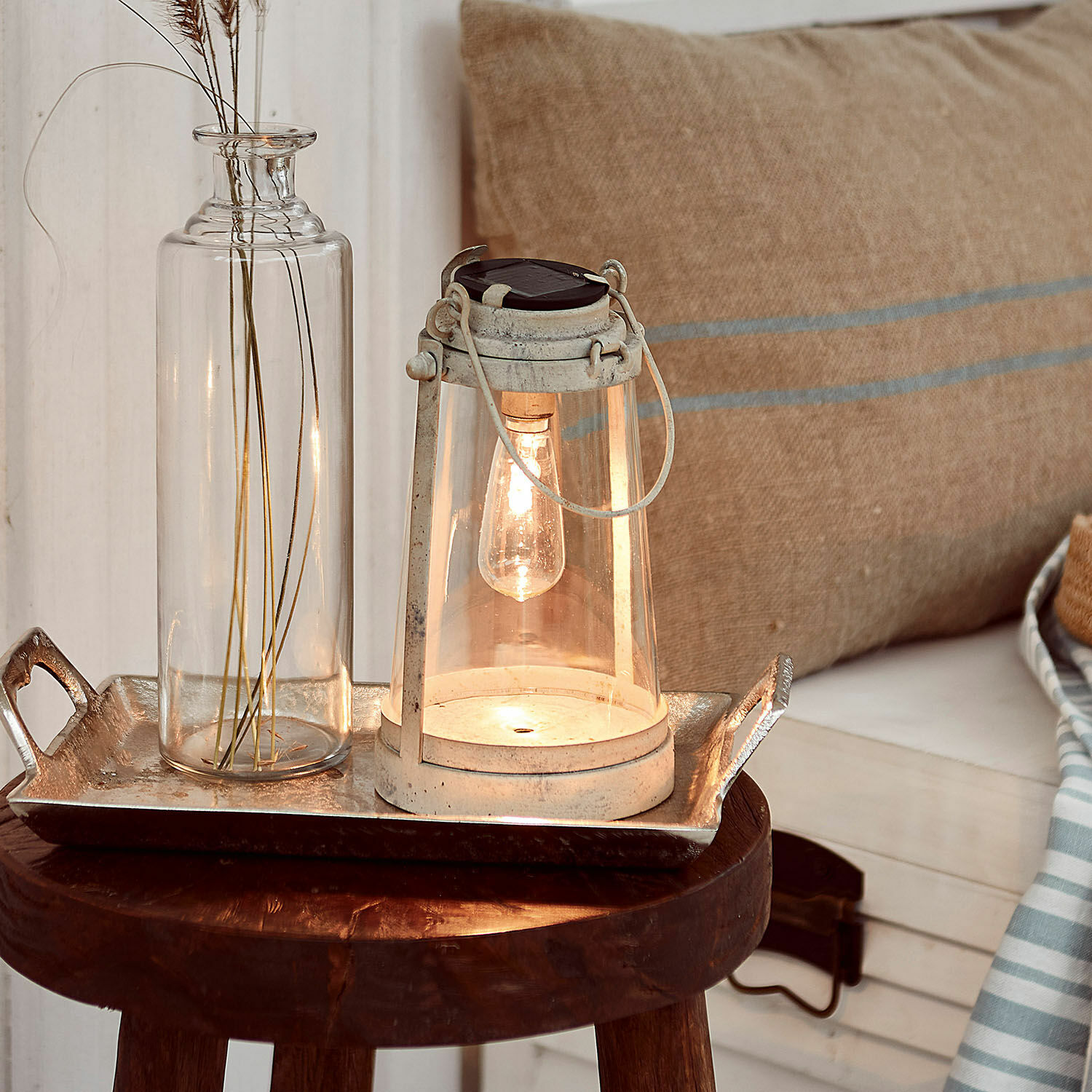 Lantaarn op zonne-energie Chénens Witte metalen lantaarn met helder glas en gloeilamp op houten kruk met decoratie