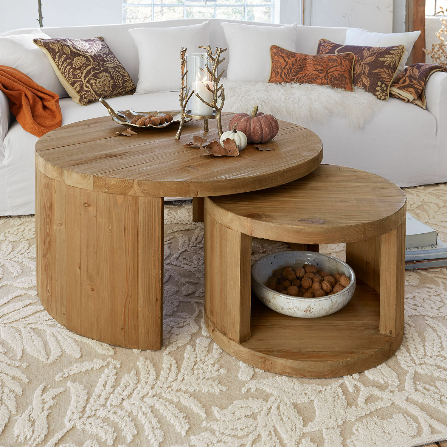 Salontafel set van 2 Torivine Twee ronde salontafels van natuurlijk grenenhout op een lichte vloerkleed met herfstdecoratie