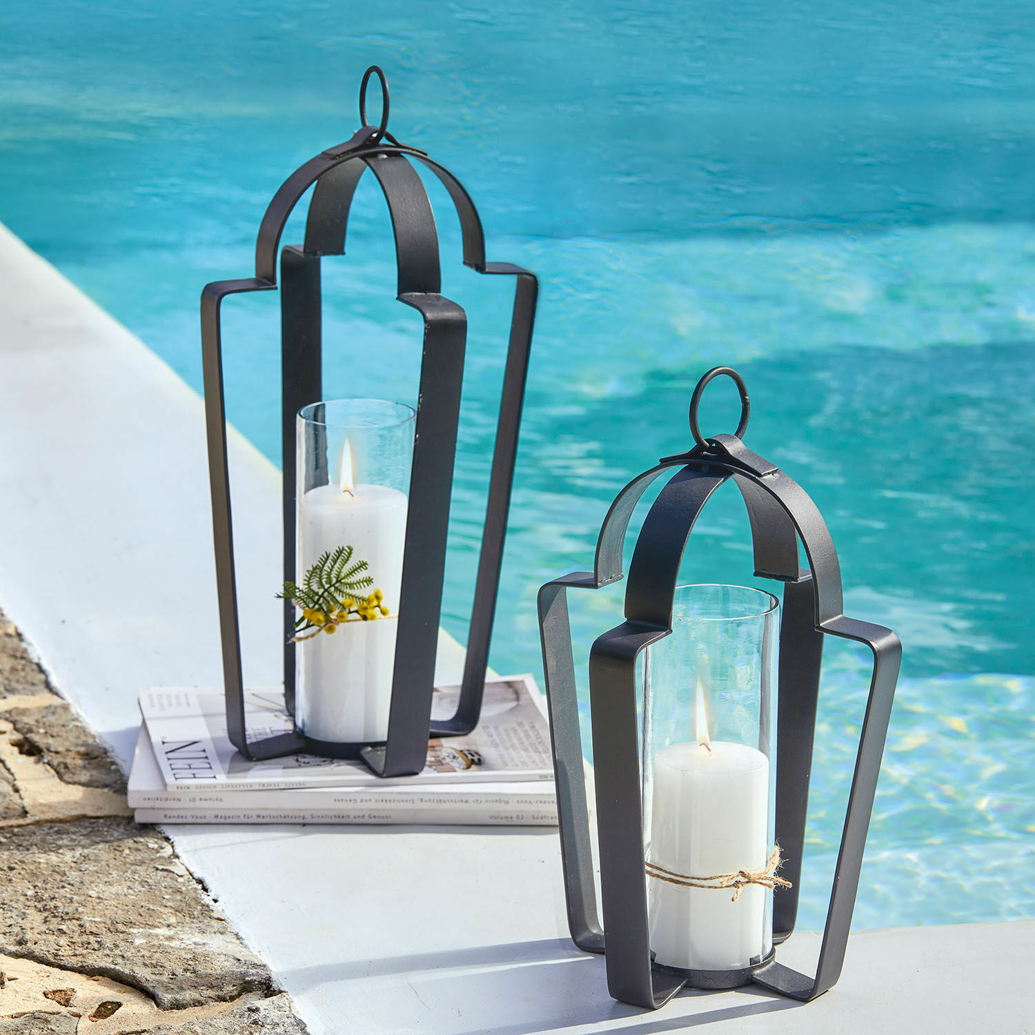 Lanternes noires en métal avec bougies blanches au bord de la piscine, décoration extérieure