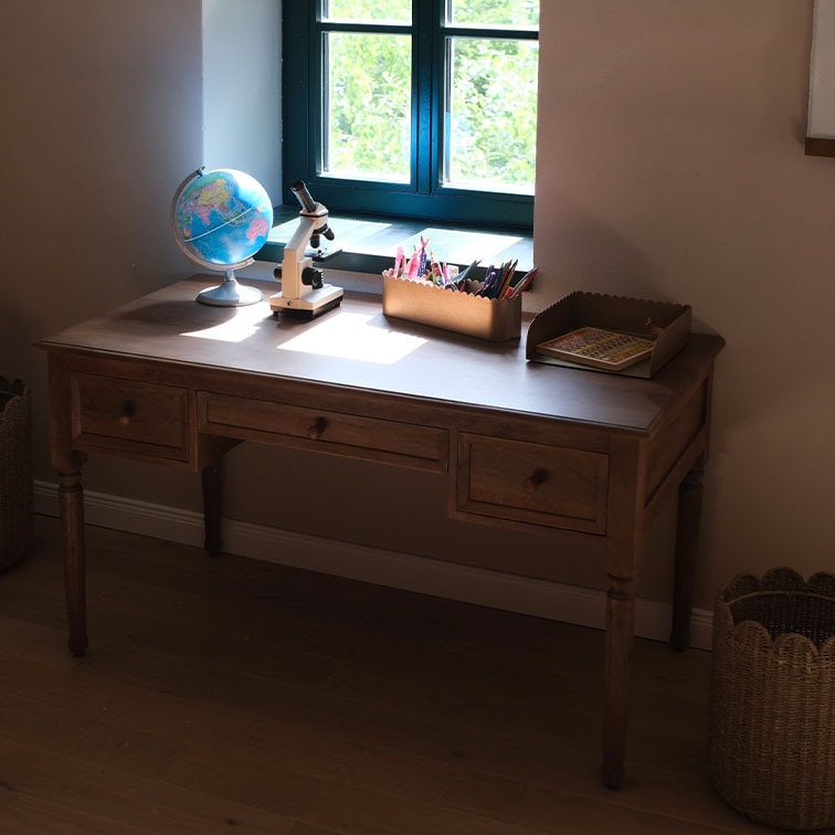 Bureau en bois avec trois tiroirs près d'une fenêtre, globe et microscope sur le dessus