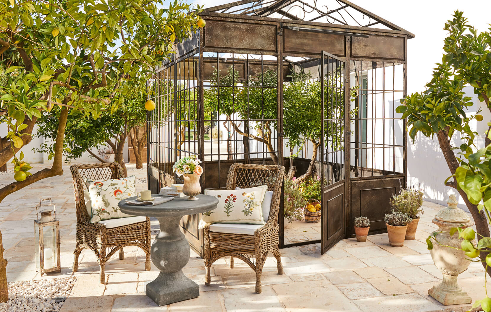 Middellandse Zee tuin met metalen prieel, rotan stoelen en stenen tafel op het terras
