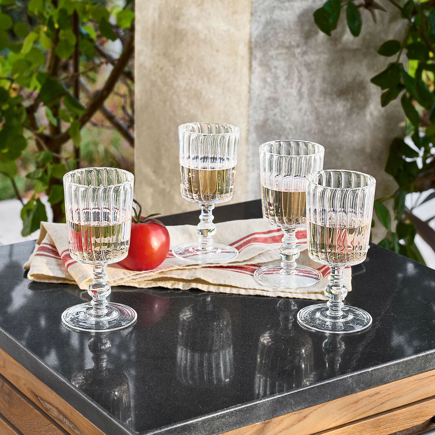 Lot de 4 verres Lianzo Quatre verres transparents en verre strié avec boisson claire sur table noire brillante