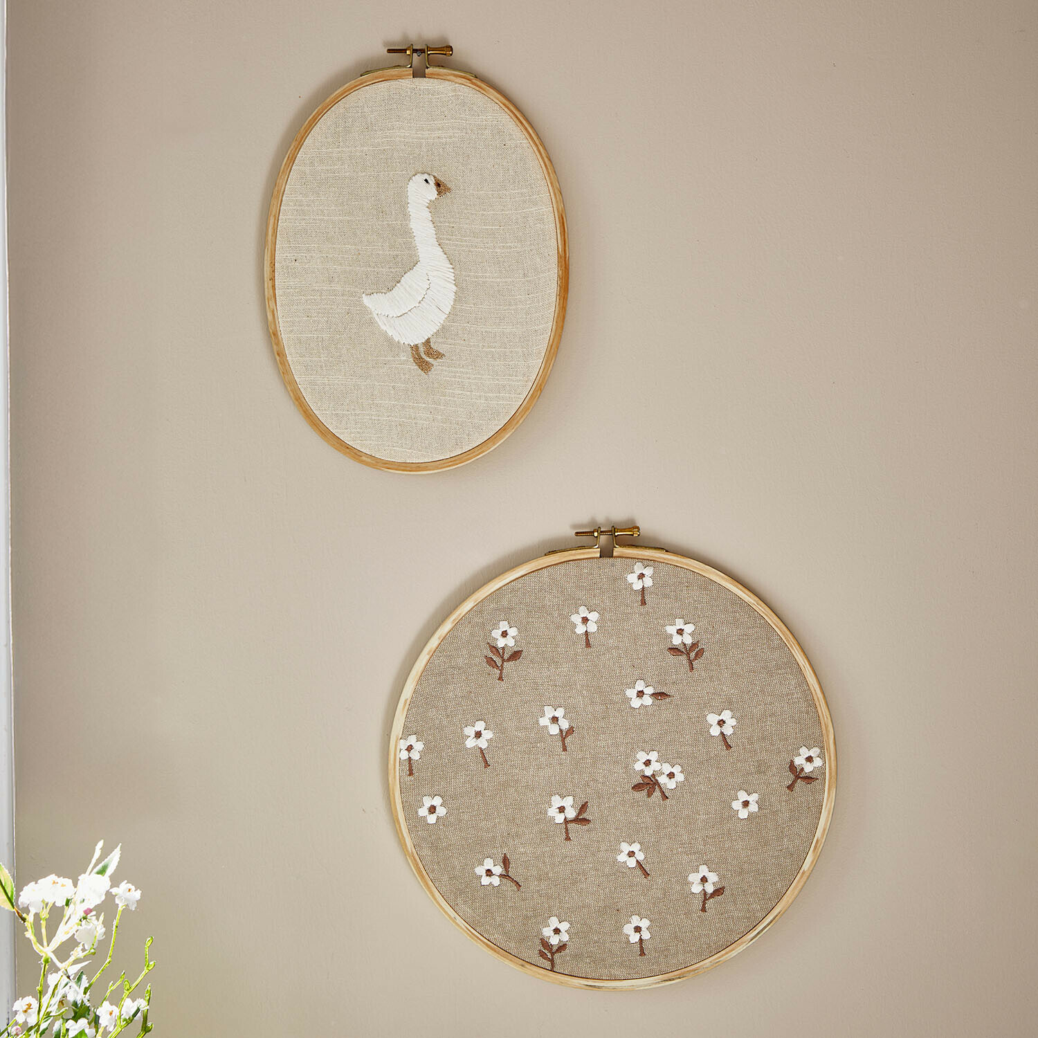 Lot de 2 tableaux Tillyboo Deux cercles à broder en lin naturel avec une oie blanche et un motif floral sur le mur