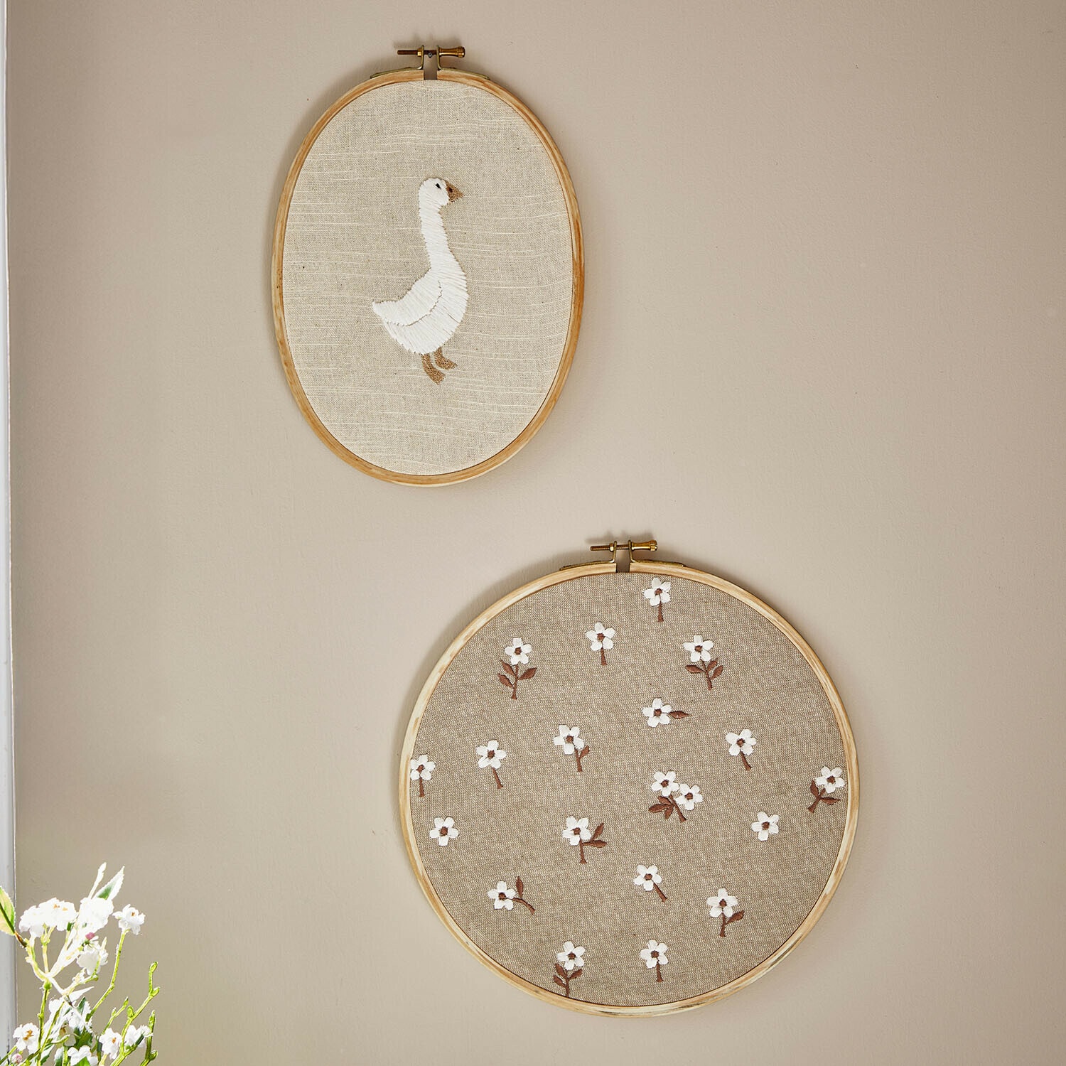 Lot de 2 tableaux Tillyboo Deux cercles à broder en lin naturel avec une oie blanche et un motif floral sur le mur