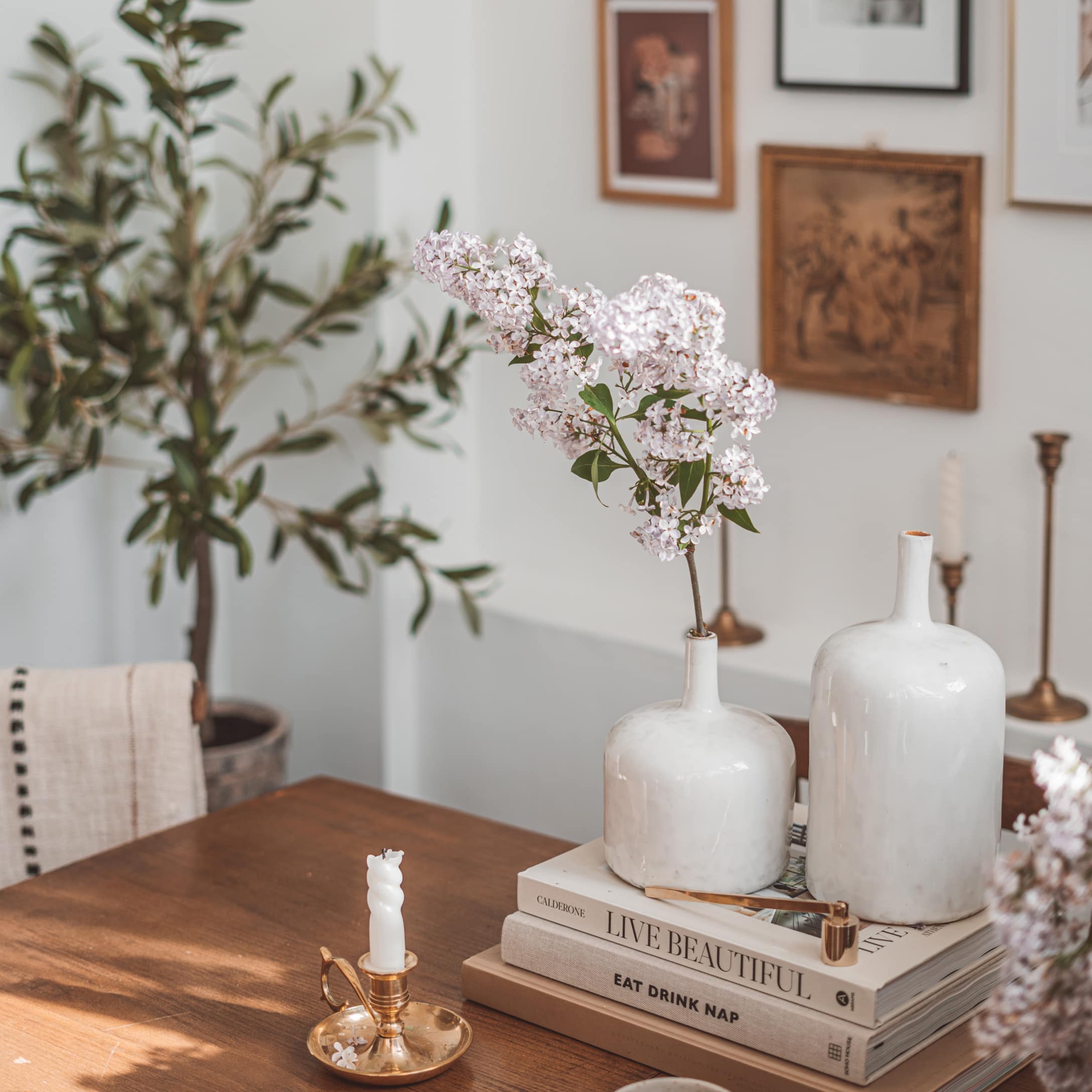 Witte keramische vazen op houten tafel met bloemen en gouden vintage kandelaar