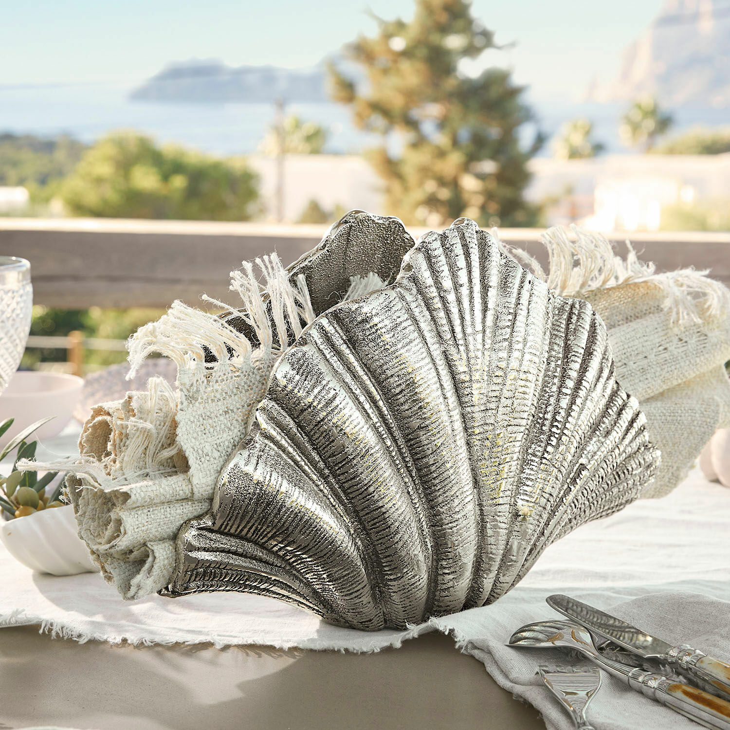 Objet décoratif Montarel Décoration en métal argenté en forme de coquillage avec serviettes en lin naturel sur table extérieure