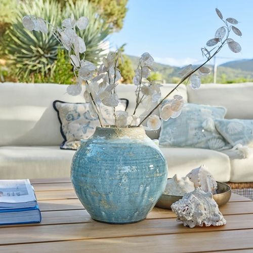 Vase en céramique bleue sur table en bois avec décoration de plantes séchées et coquillages, décoration intérieure élégante