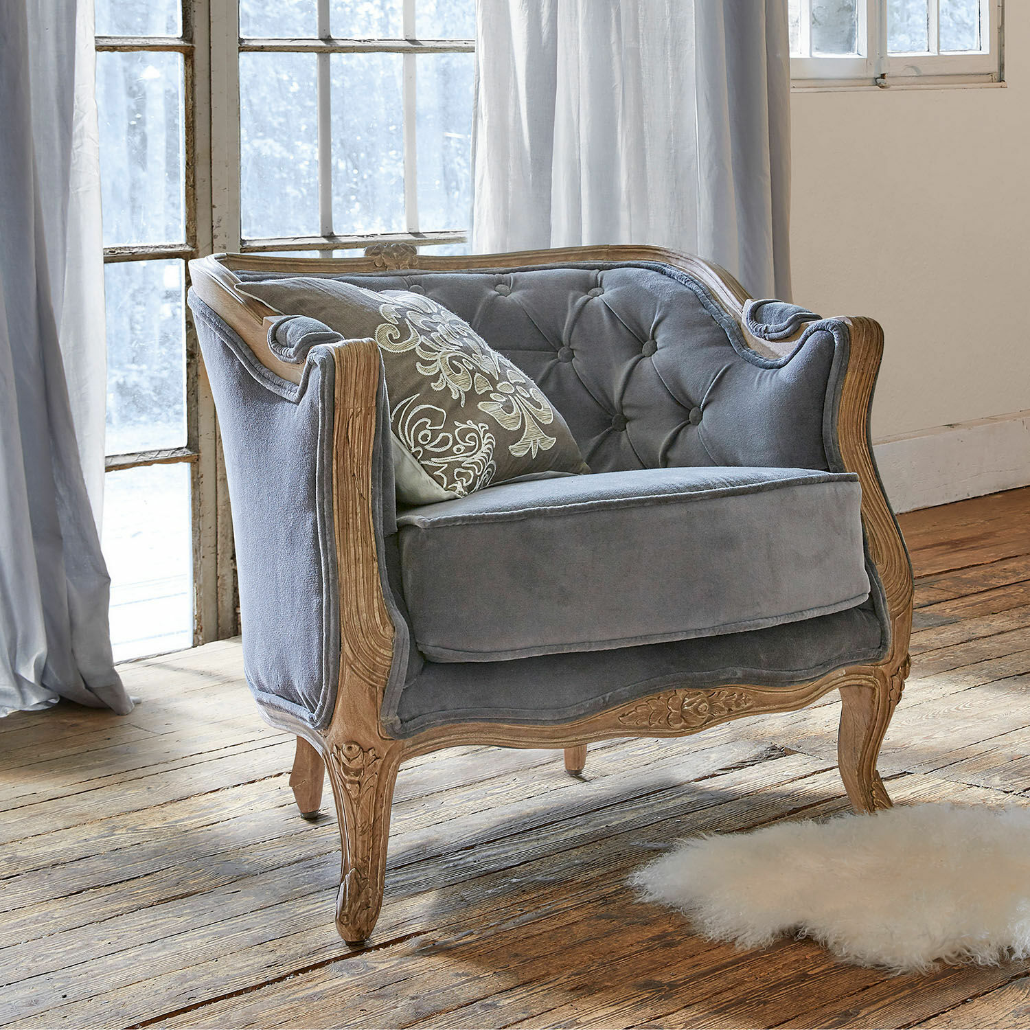 Fauteuil Annezay Grijze fluwelen bank met gesneden houten frame op houten vloer in lichte kamer