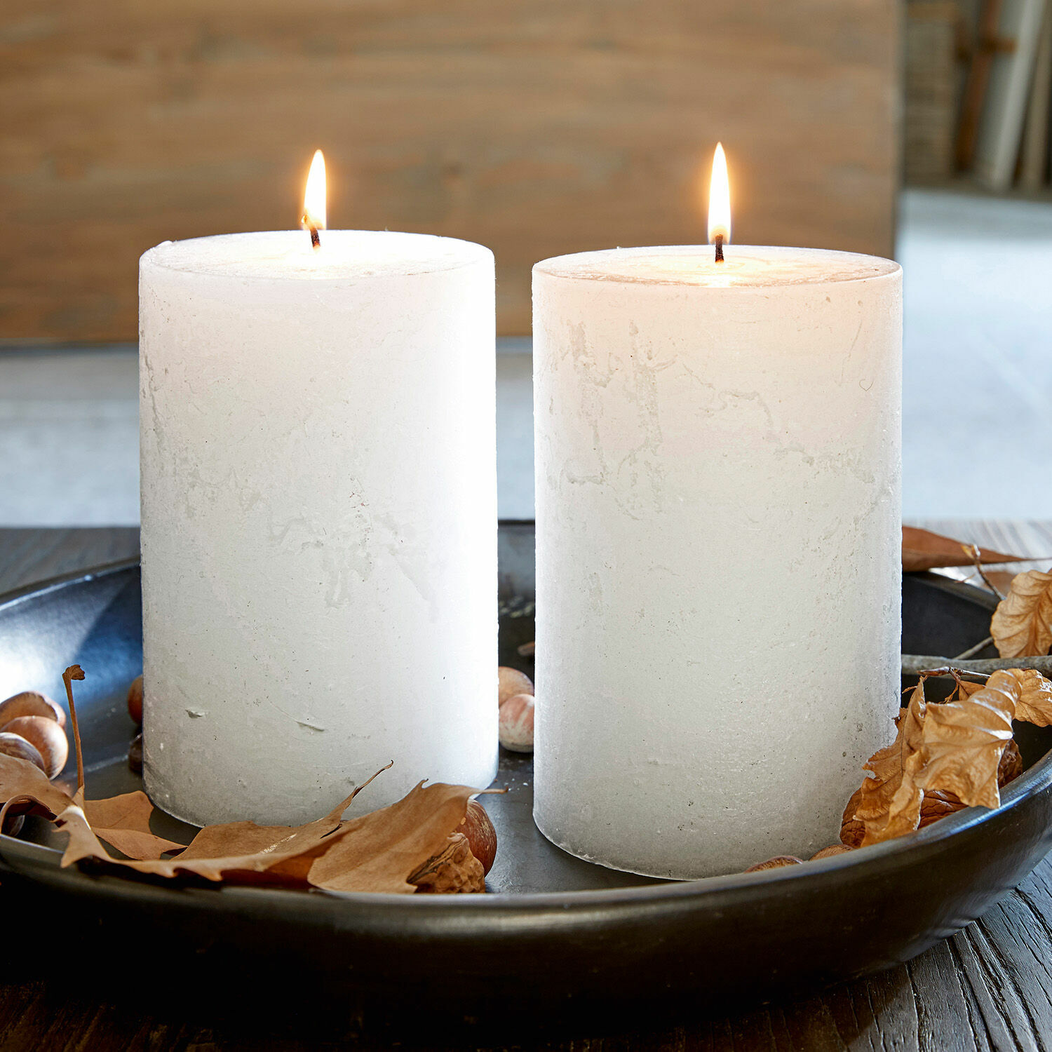 Kaars set van 2 Oviedo Twee witte kaarsen van was op een zwart dienblad met droge bladeren en noten, herfstdecoratie