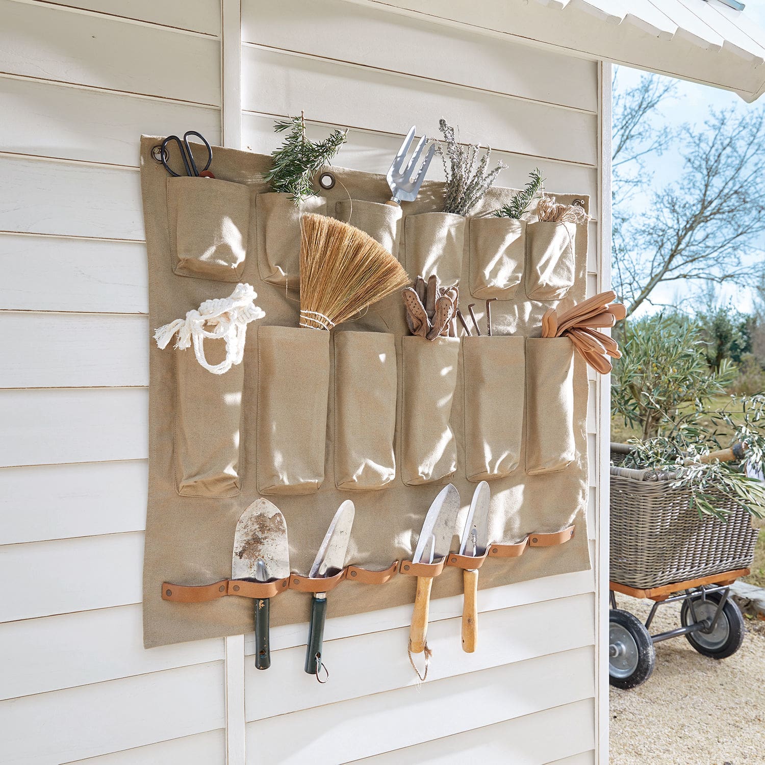 Beige stoffen organizer met zakken en leren houders voor tuingereedschap en scheppen