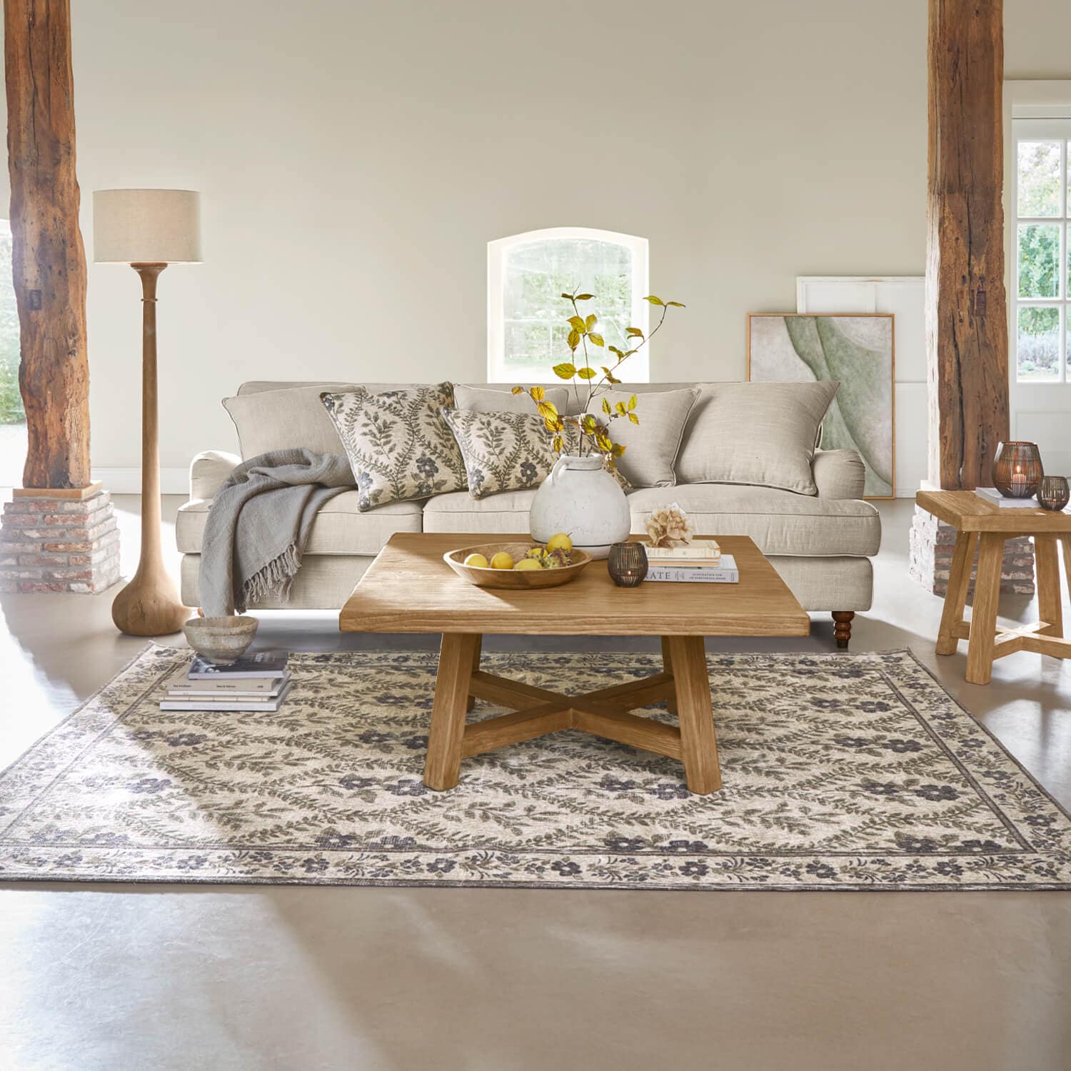 Gezellige woonkamer met beige bank, houten salontafel en vloerkleed met bloemenpatroon