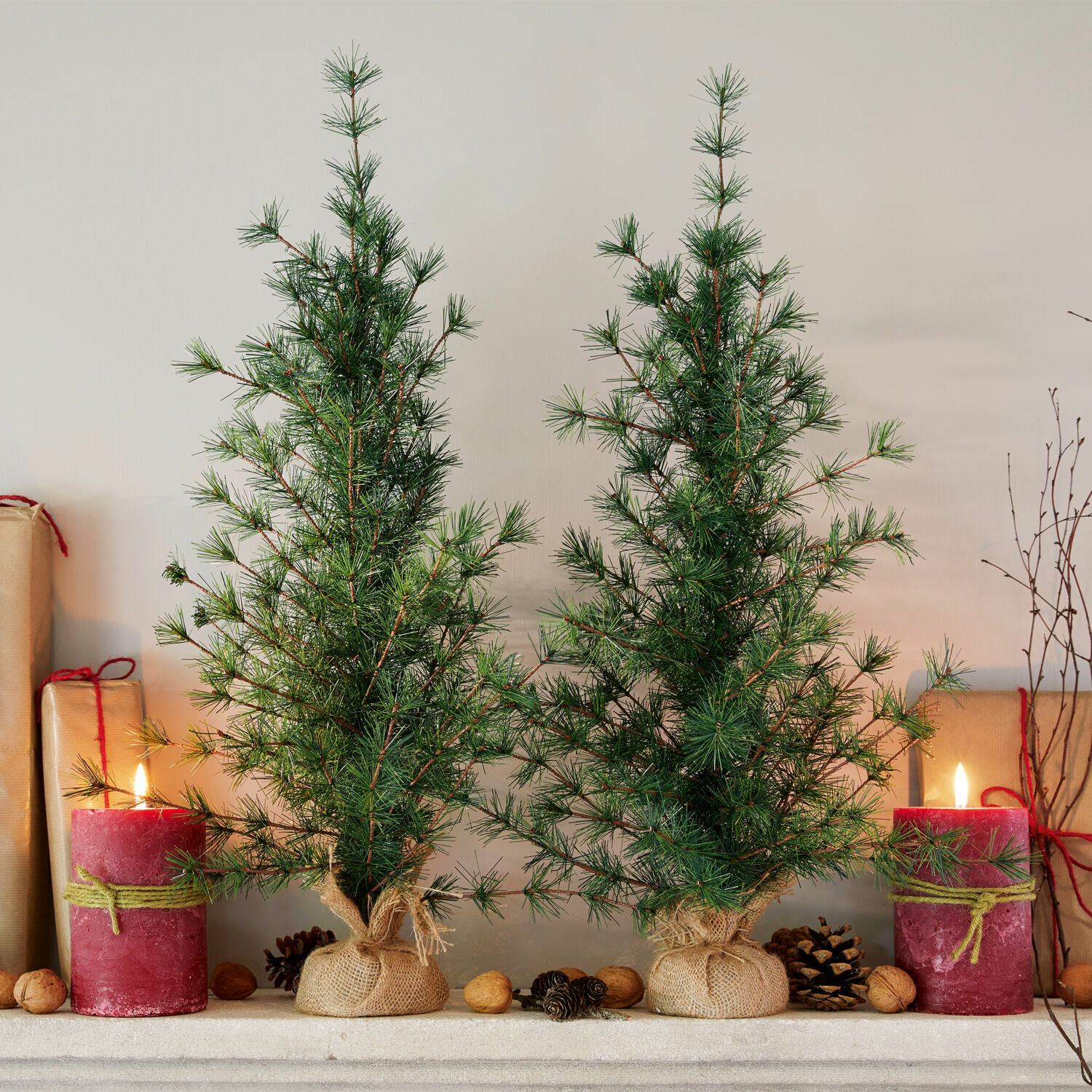 Lot de 2 sapins décoratifs Bohicon Deux petits sapins verts en toile de jute avec bougies rouges et noix sur la cheminée
