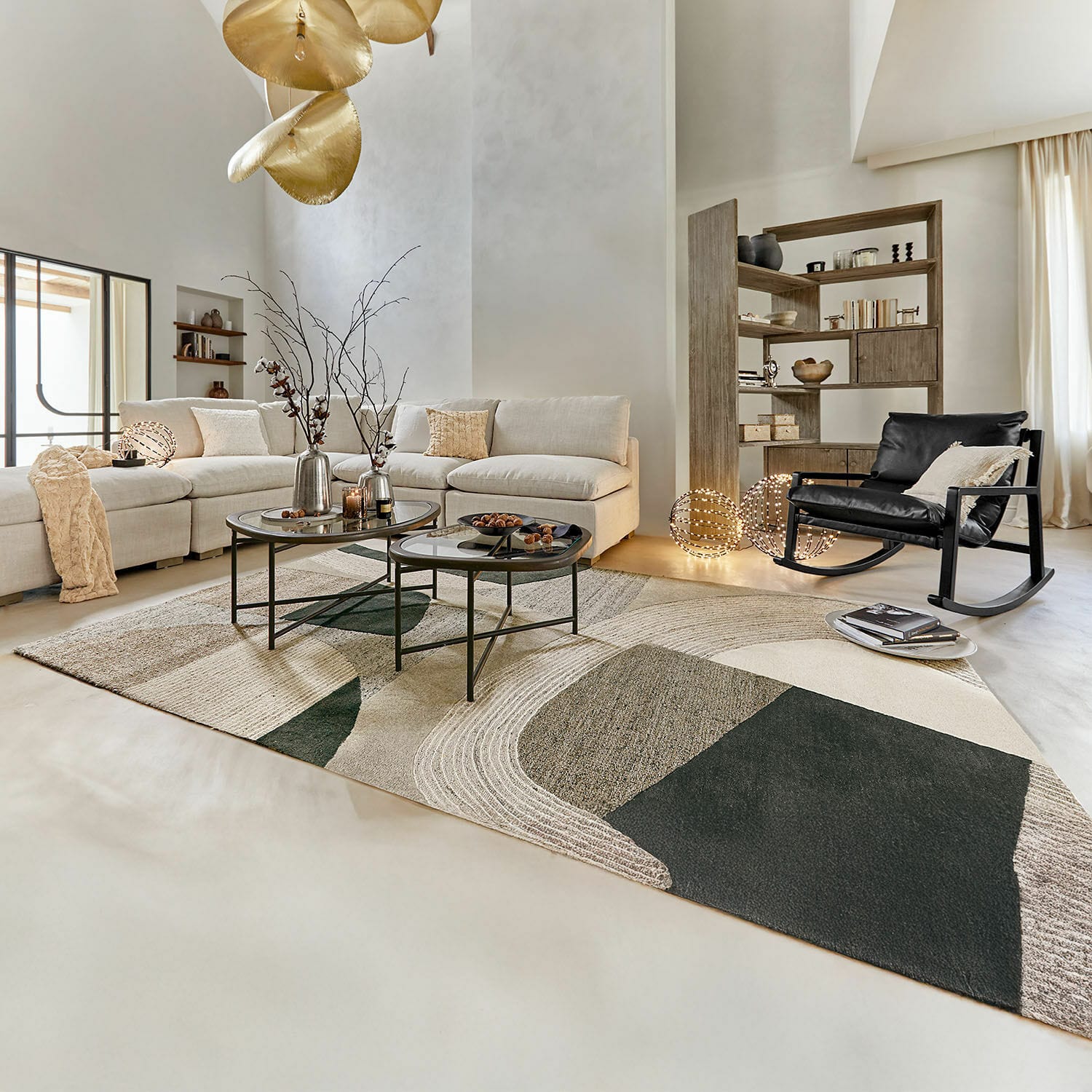 Moderne woonkamer met beige bank, zwarte schommelstoel en geometrisch vloerkleed in natuurlijke tinten