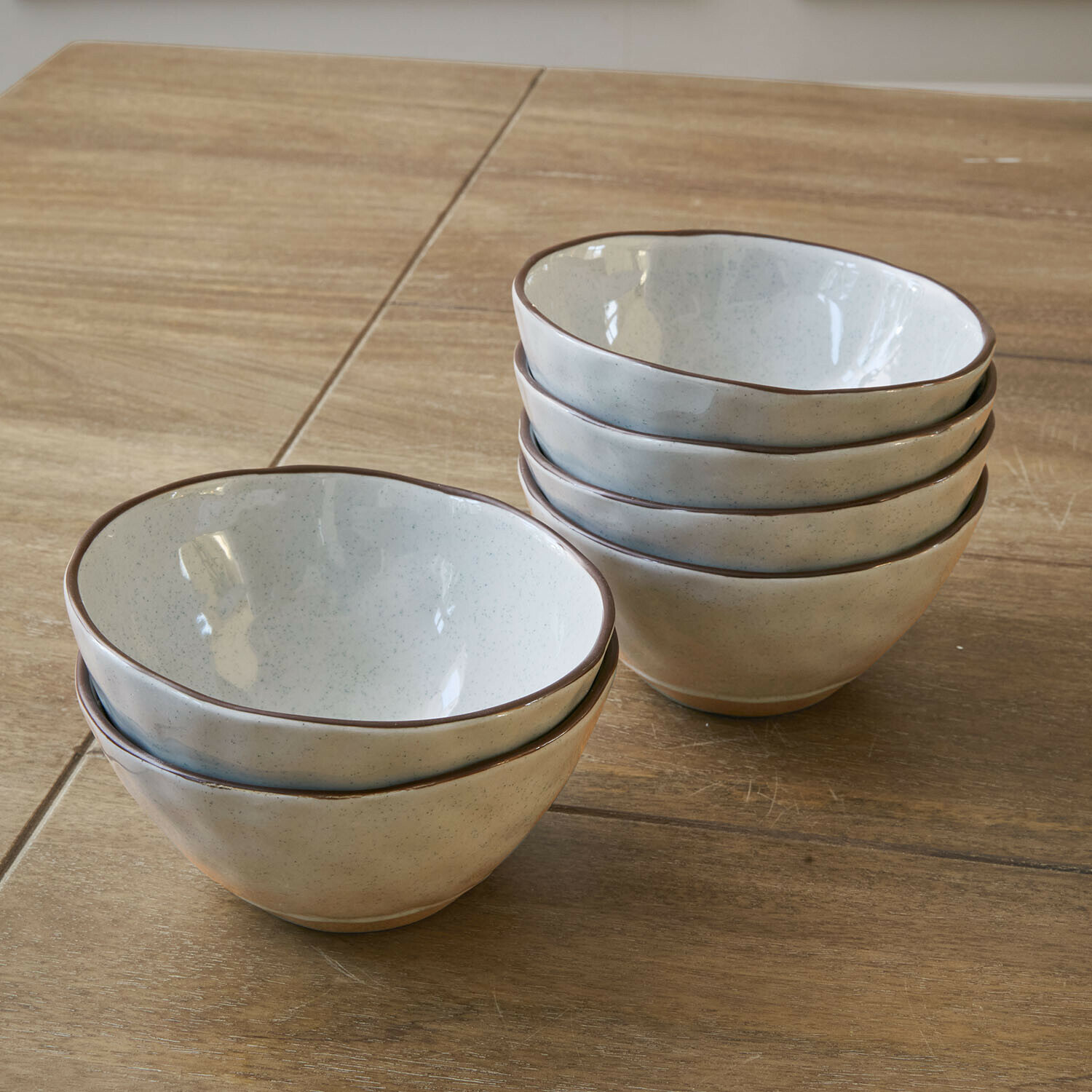 Lot de 6 bols Biarré Ensemble de six bols en céramique crème avec bord brun posés sur une table en bois
