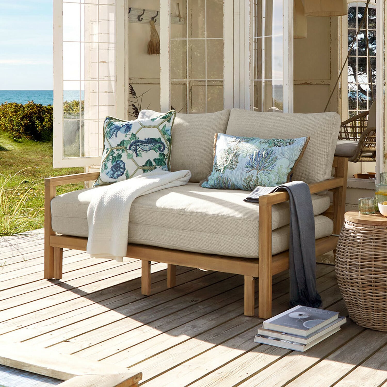 Uitschuifbare bank Tjorna Lichtbeige bank met houten frame op terras met uitzicht op tuin en zee
