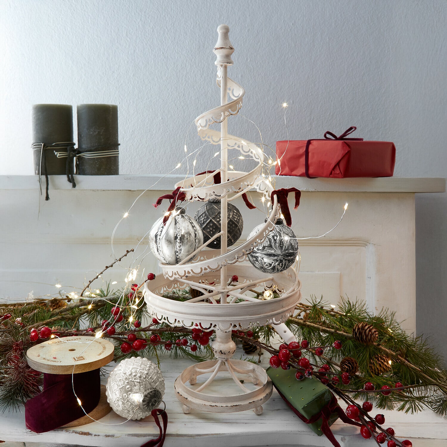 Sierboom Gerzat Witte metalen kerstdecoratie met hangende ballen en LED-lichtjes, rode cadeaus en groene takken op de achtergrond