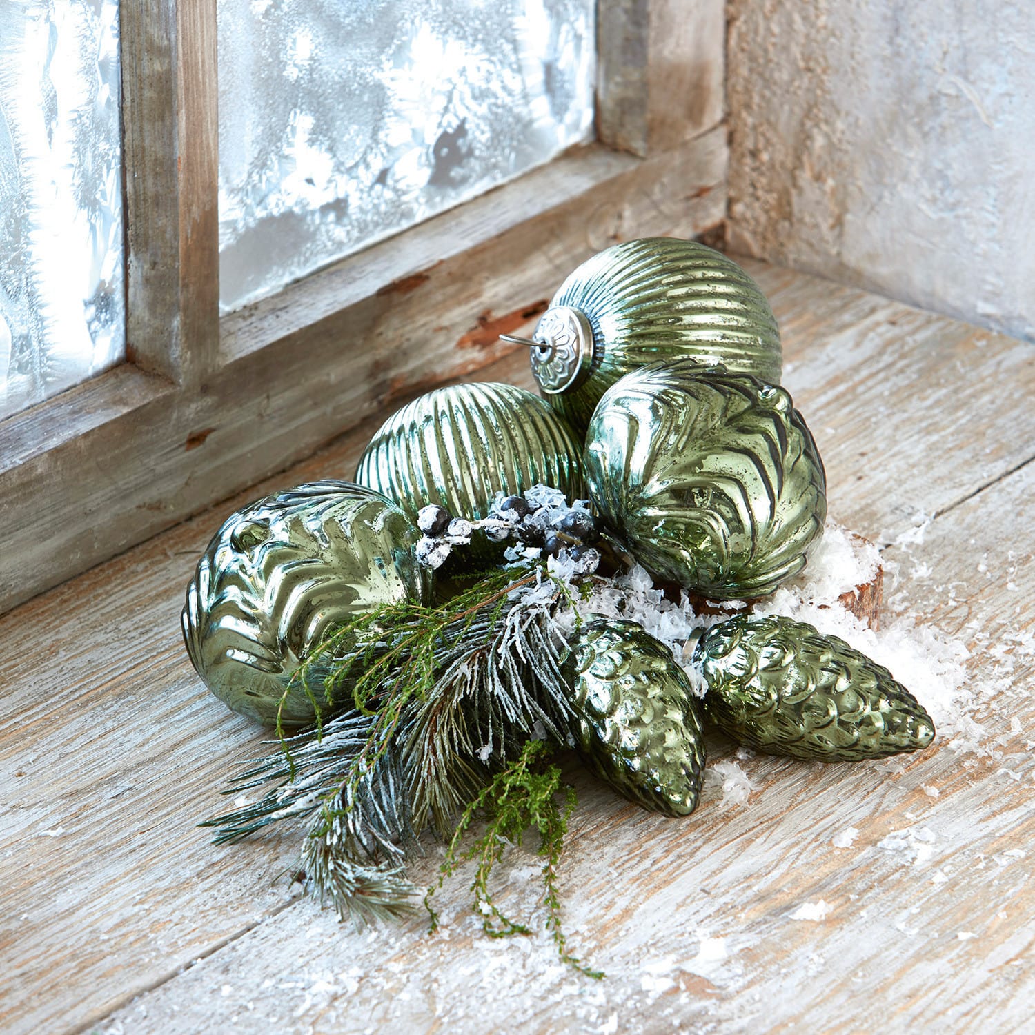 Kerstversiering set van 6 Silverhill Groene glazen kerstballen met verschillende texturen, takken en nepsneeuw op een houten vensterbank